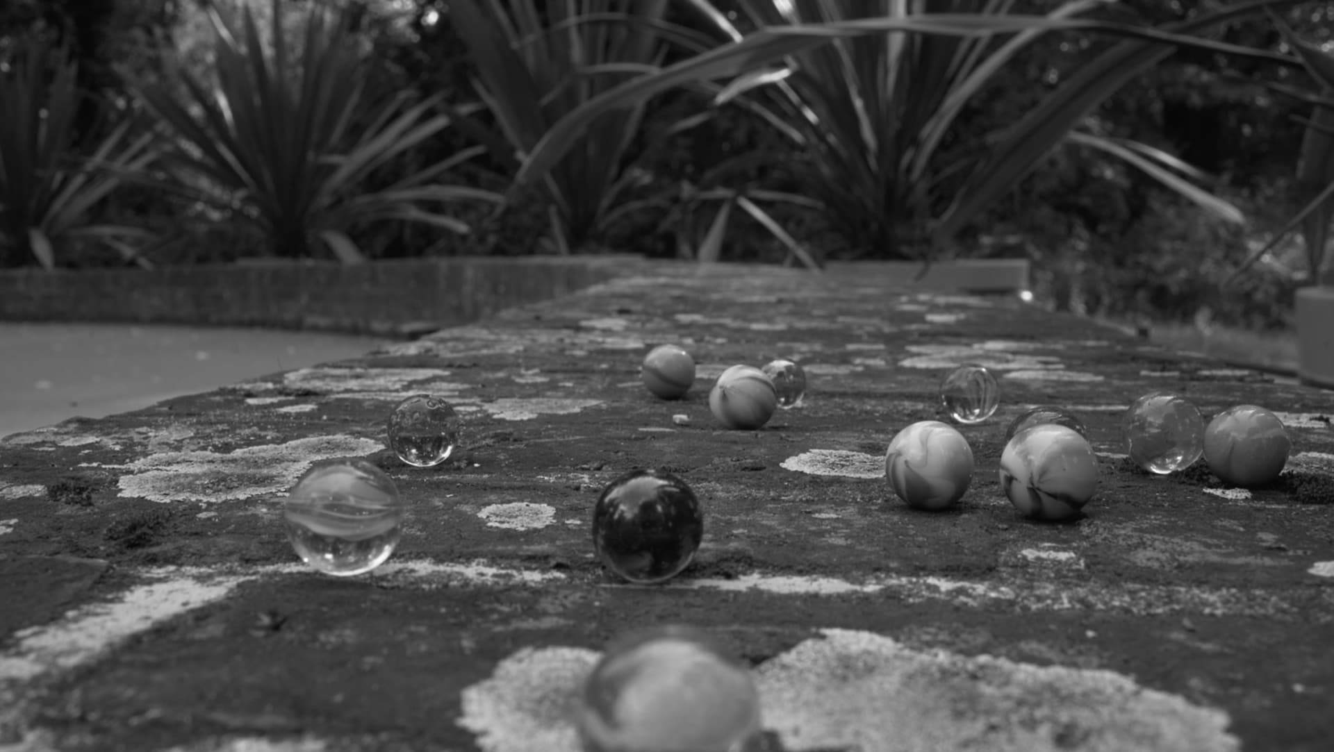 Poetical Digital Storytelling by Tina Bikic, showing close-up of marbles scattered on the ground, evoking play and memory.
