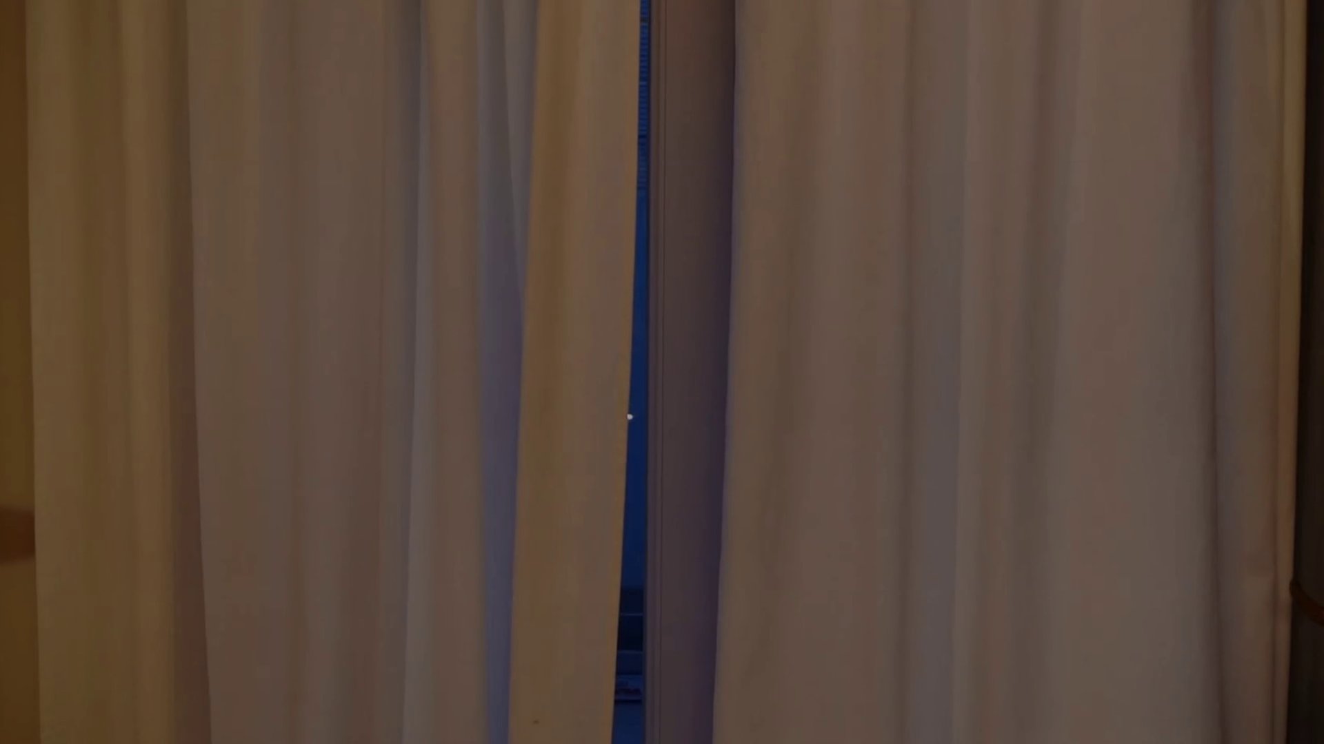 Film still from "Fear" by Tina Bikic showing a close-up of a swimmer wearing yellow goggles, crouching among tall grass.