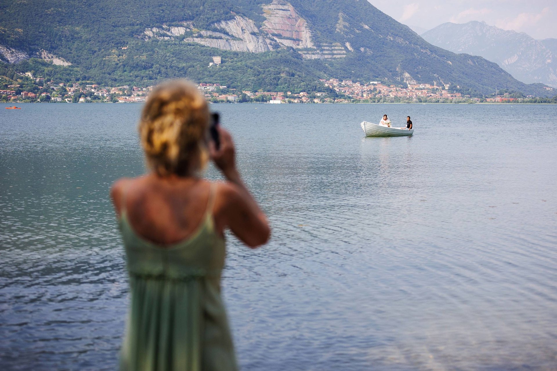 Una invitata riprende col telefonino l'arrivo della sposa su una barchetta bianca, sul lago di Como