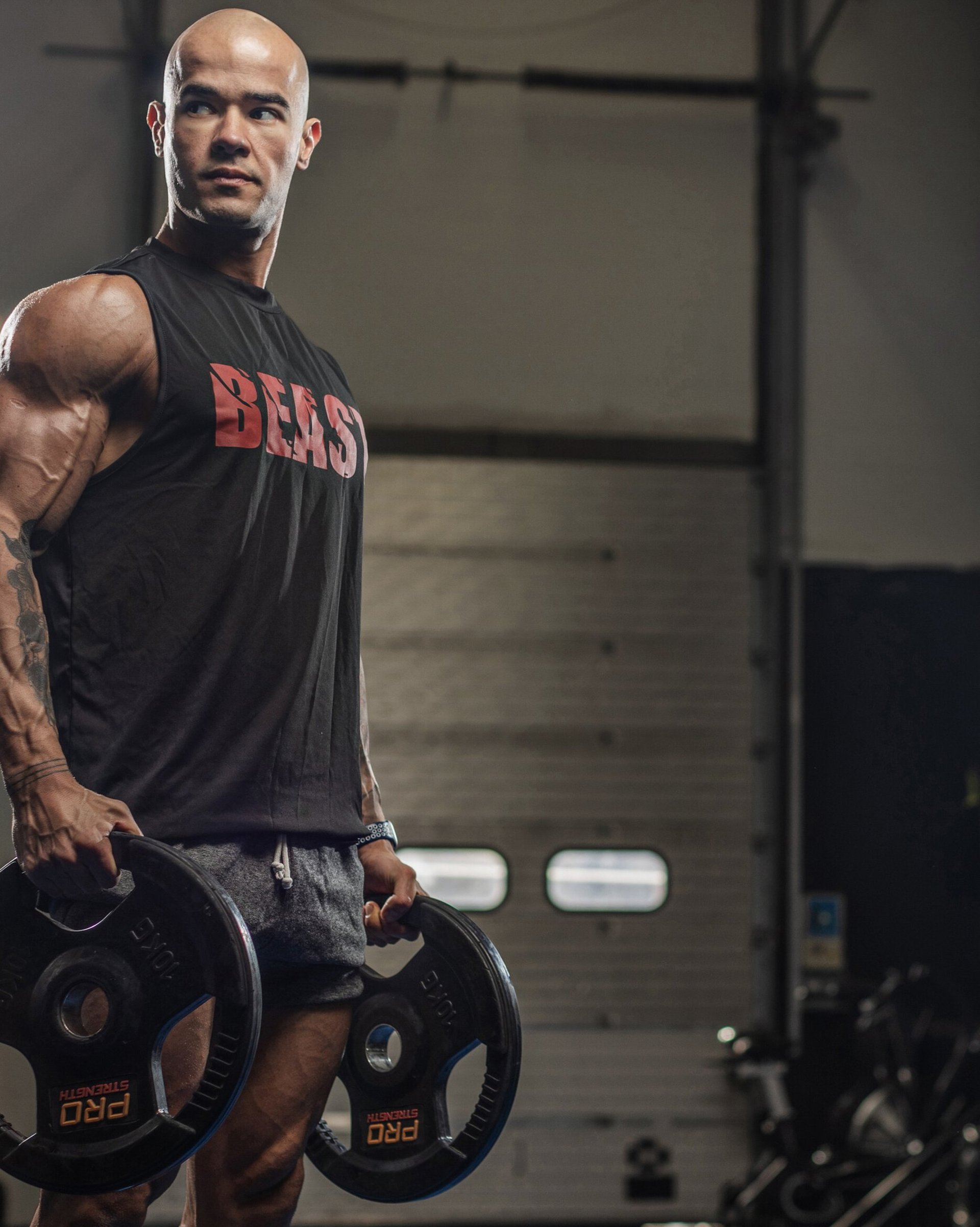 Coach Anderson, East London personal trainer, holding two weight plates.