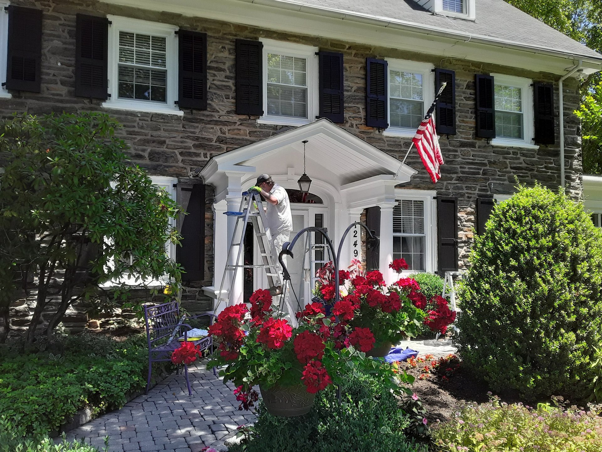 a painter on a ladder painting the front of a house