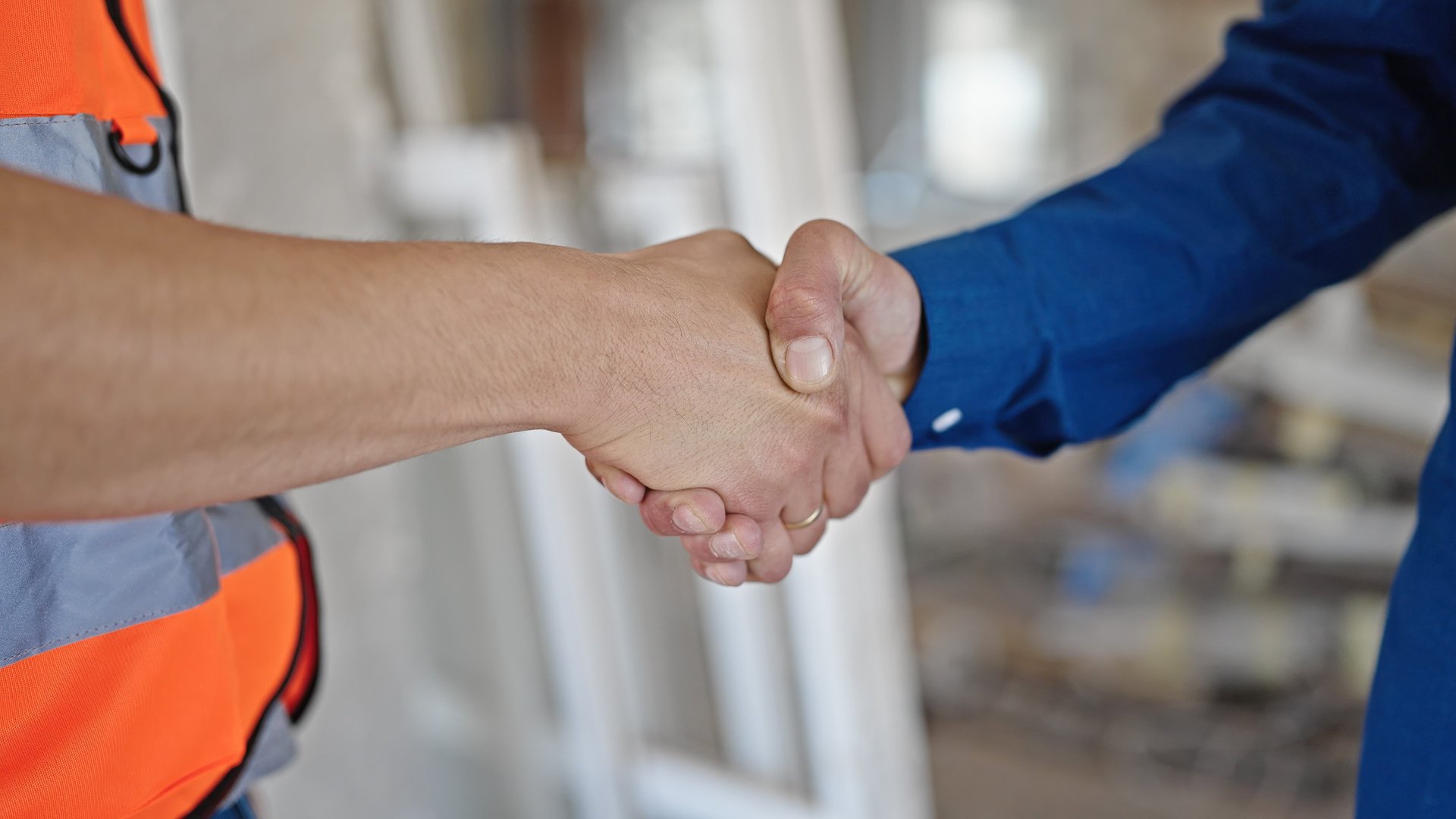 A happy homeowner and tradesperson shaking hands
