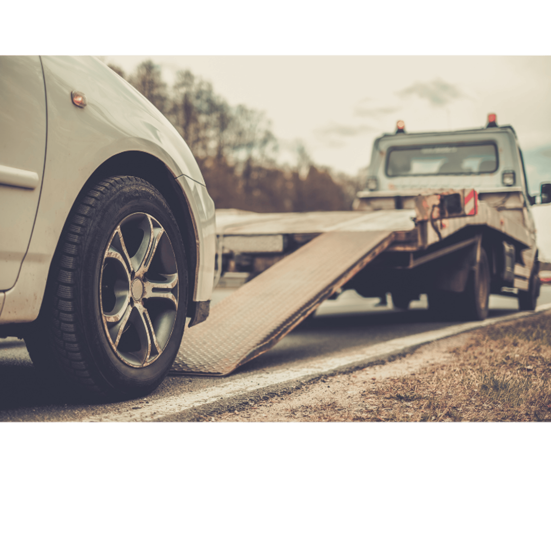 Sepia-toned image of an suv about to be loaded onto the bed of a tow truck.