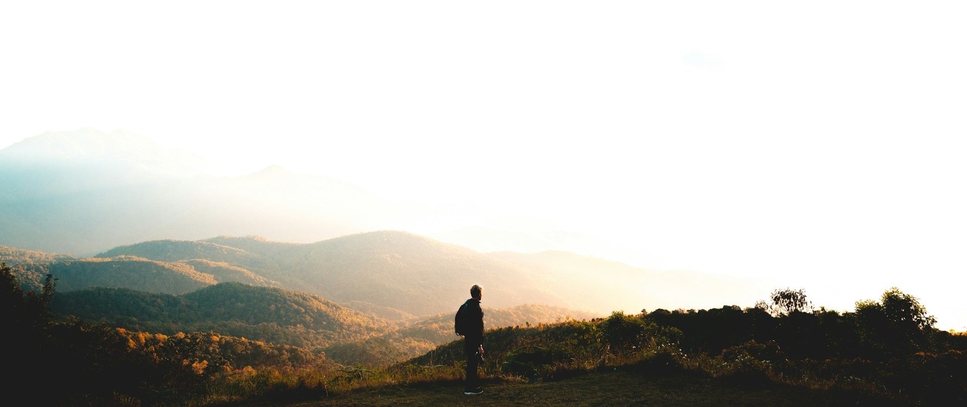 man standing near mountain under cloudy sky at daytime
