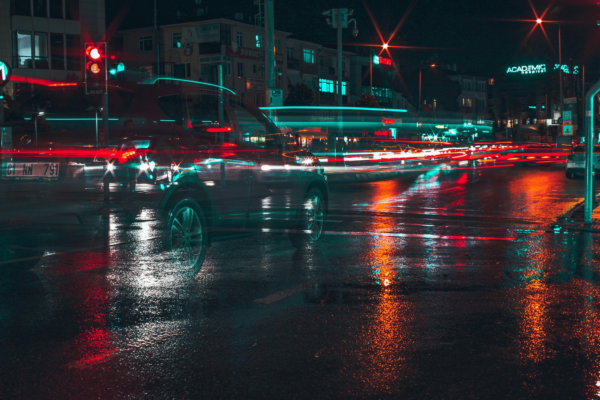 A black car driving down a street next to a forest