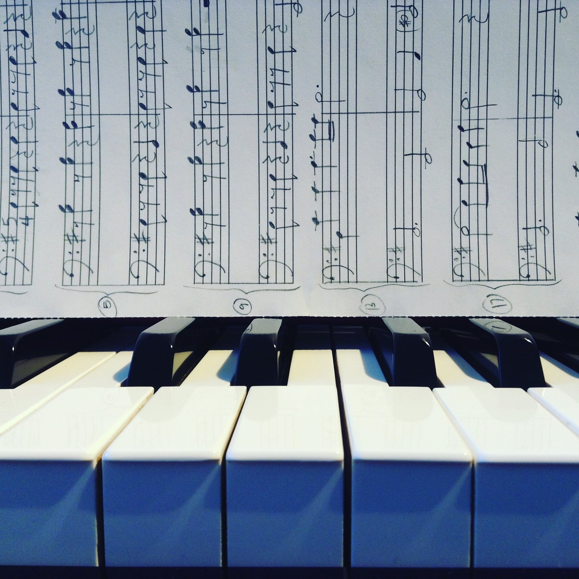 A close-up of a piano keyboard and handwritten composition by Jen Smith Lanthier