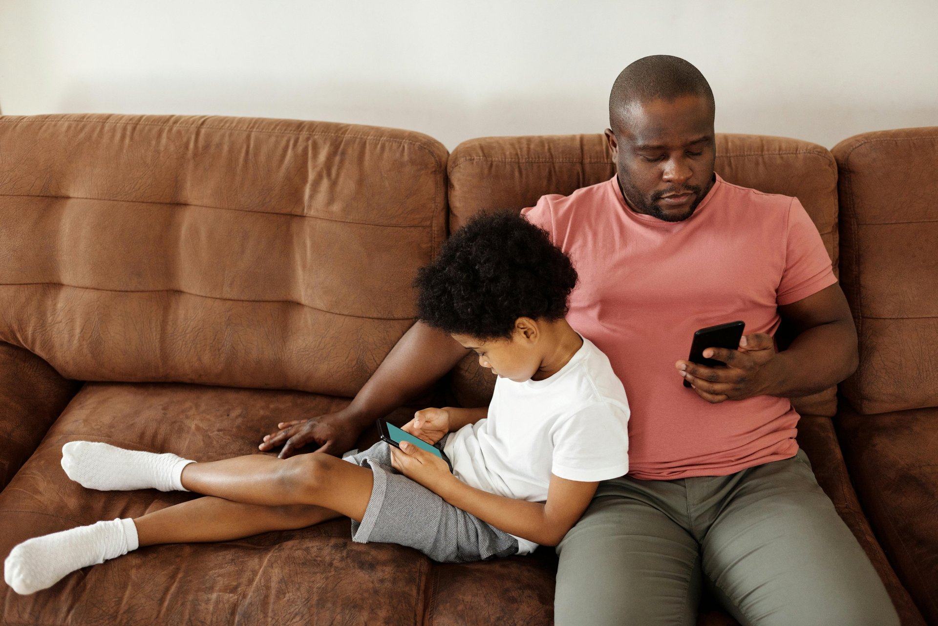 two babies and woman sitting on sofa while holding baby and watching on tablet