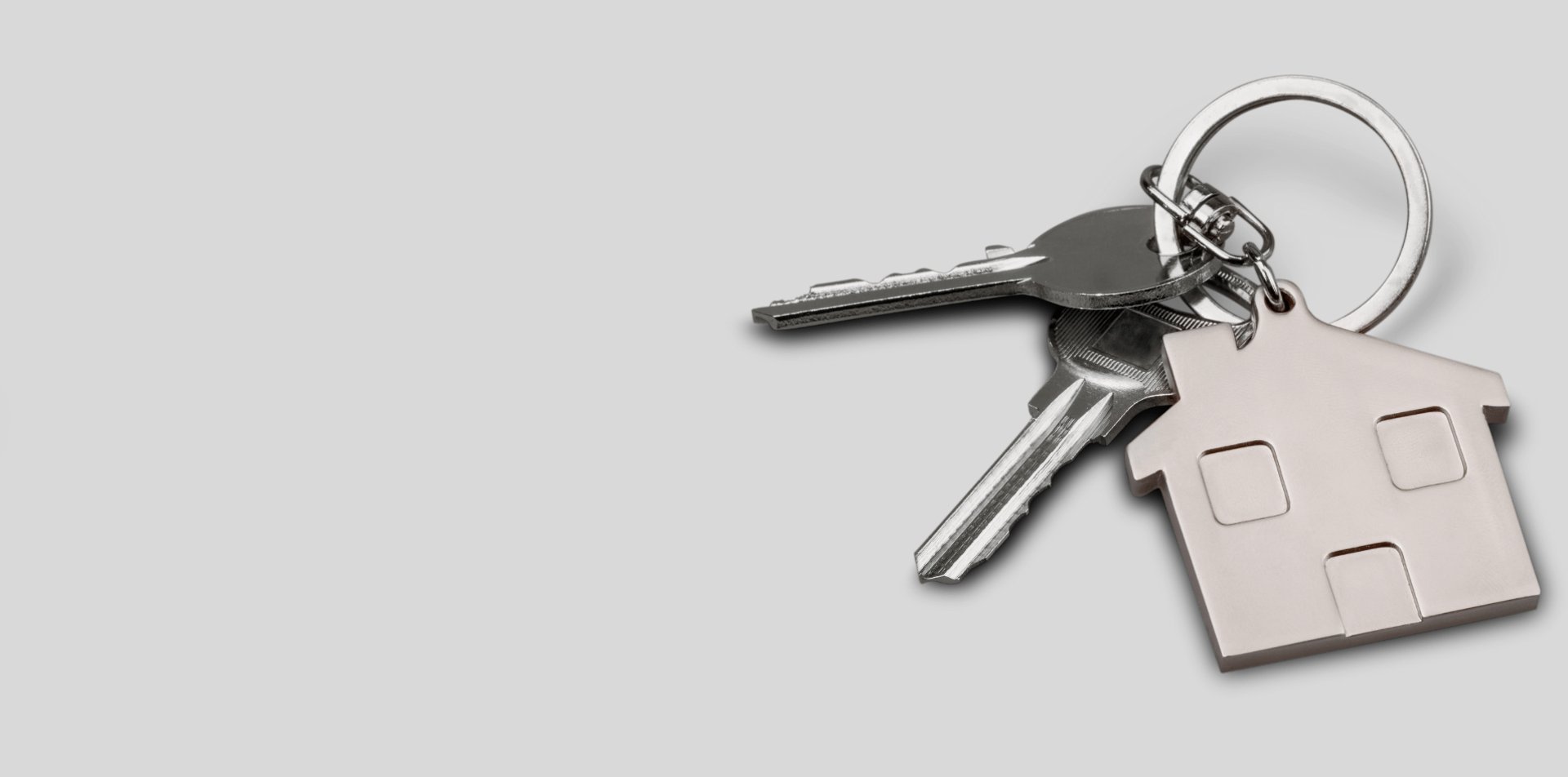A hand holding a green key to a house