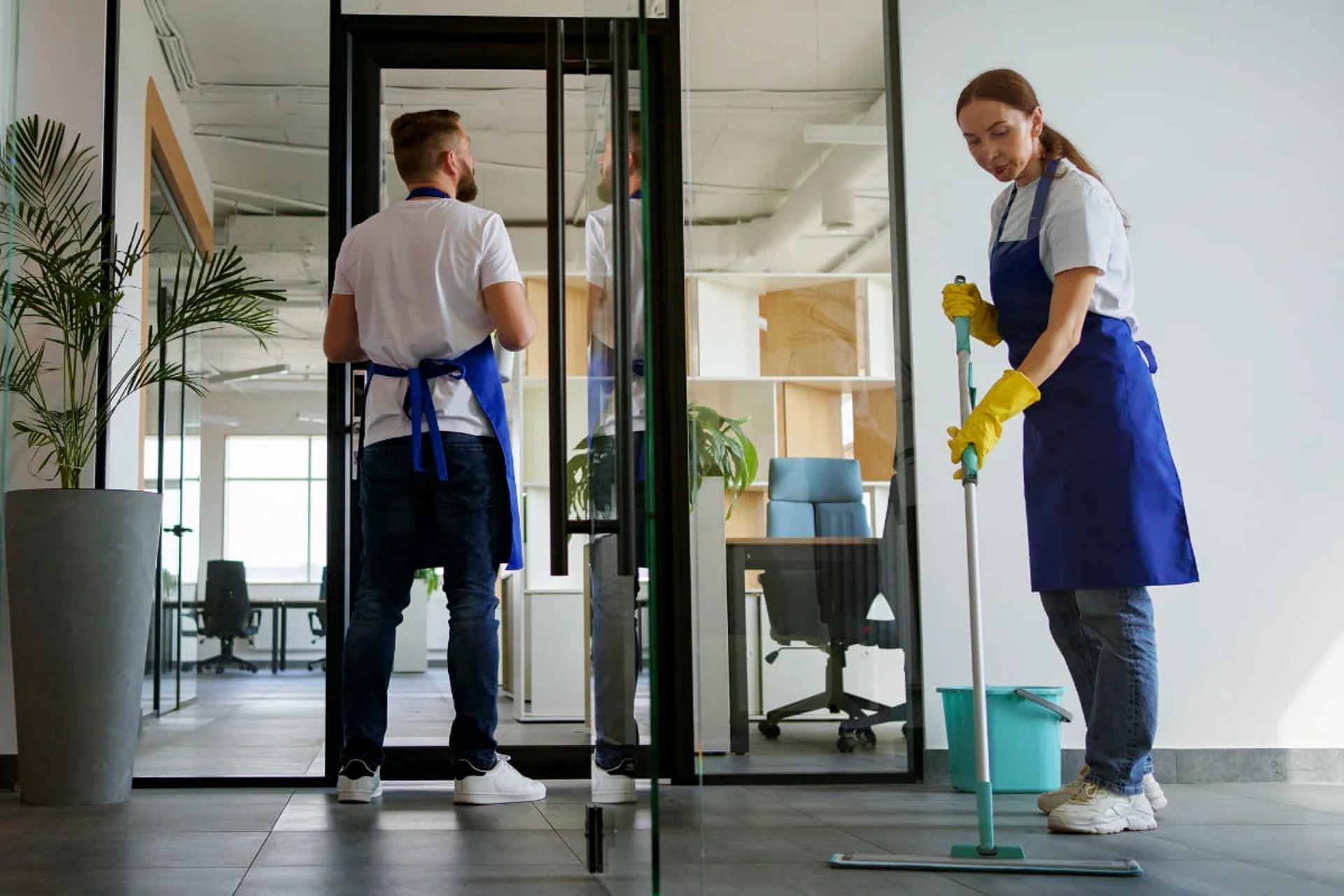 A person in yellow gloves and blue gloves cleaning a floor