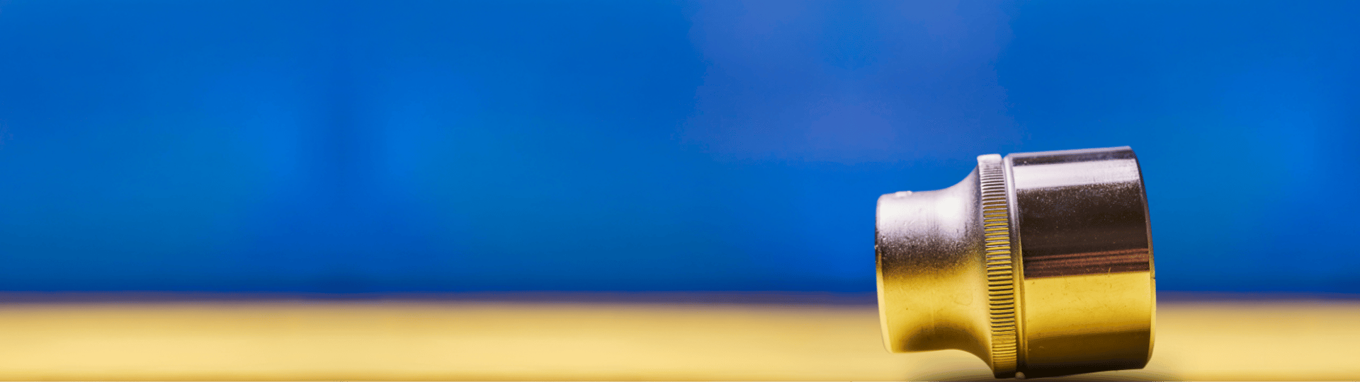 Plated head wrench on blue and yellow coloured background. Machine repair tool.