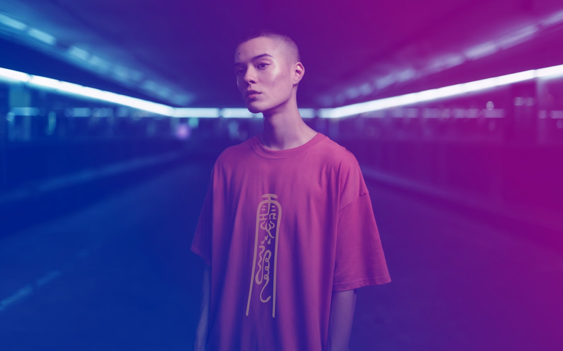man model wearing Fulutee red T-shirt with Fu talisman design, standing in a vibrant neon-lit tunnel.