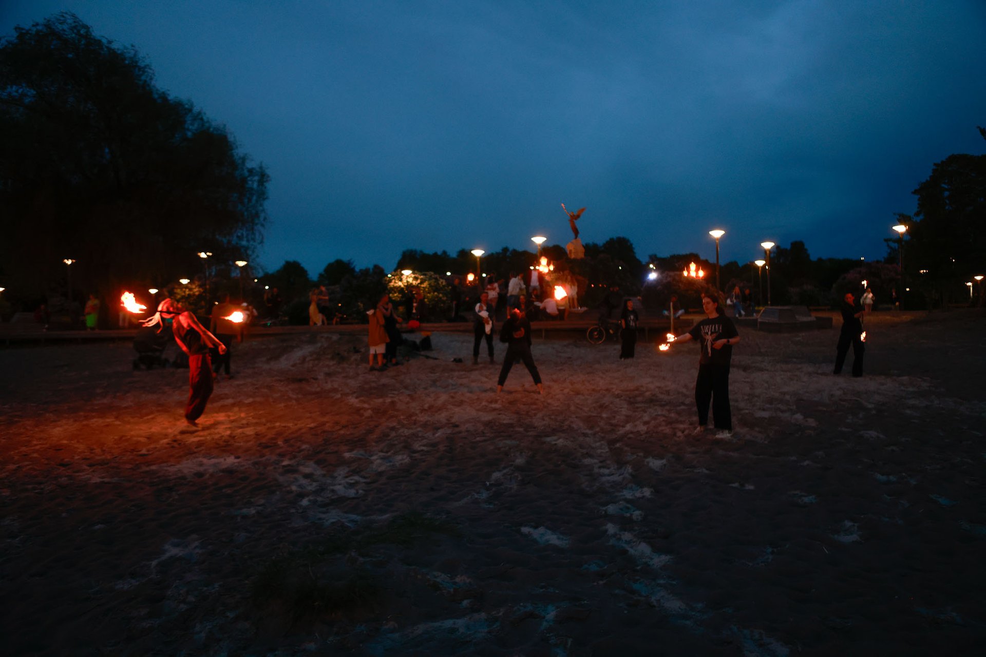 people gathered in the beach, fire dancers, people drumming and dancing in a circle