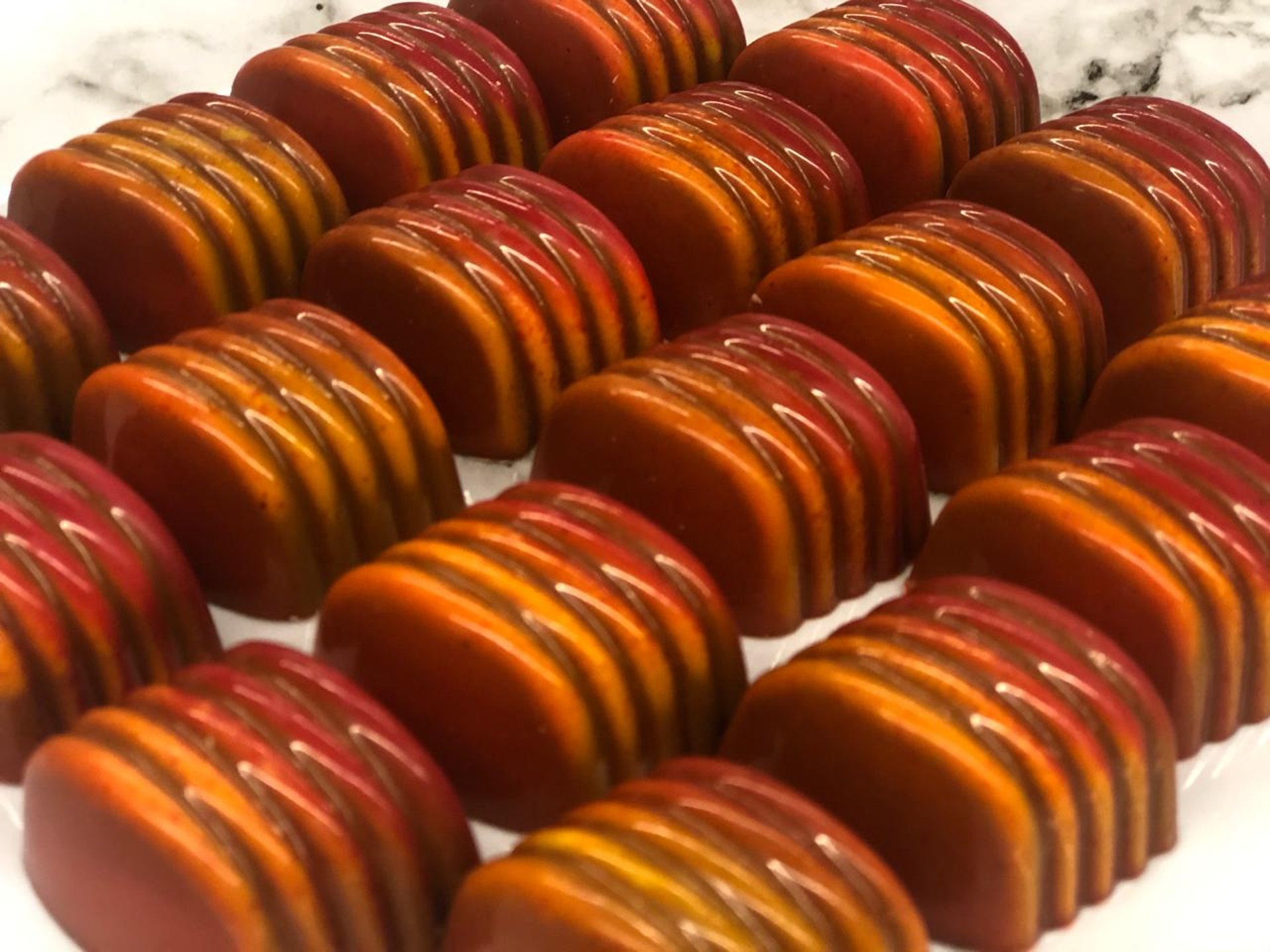 Handcrafted chocolates with cocoa butter decoration in vibrant colors luxury shine chocolates from ChocosCookiesCakes