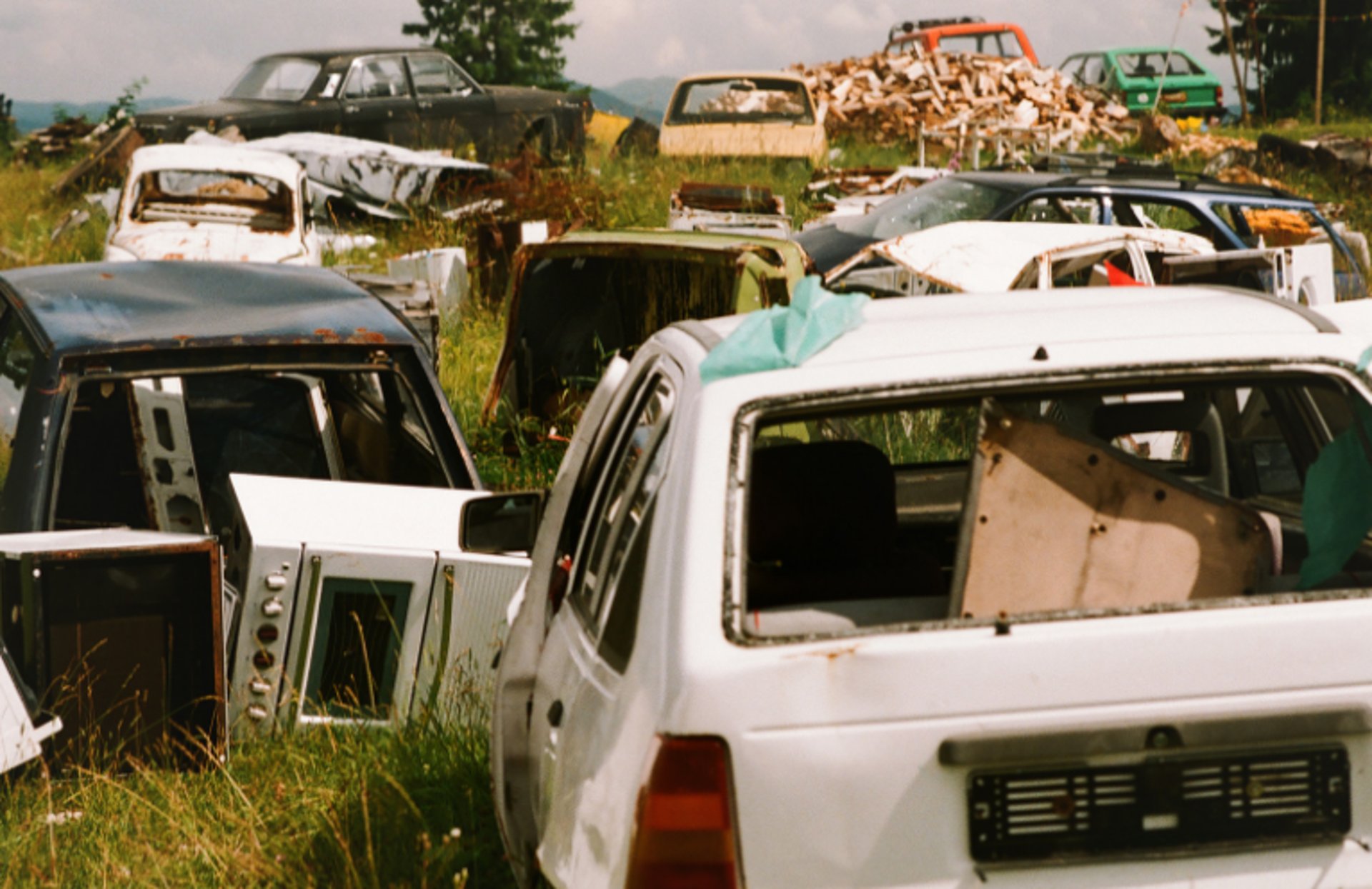 Various scrapped cars decaying in a yard.