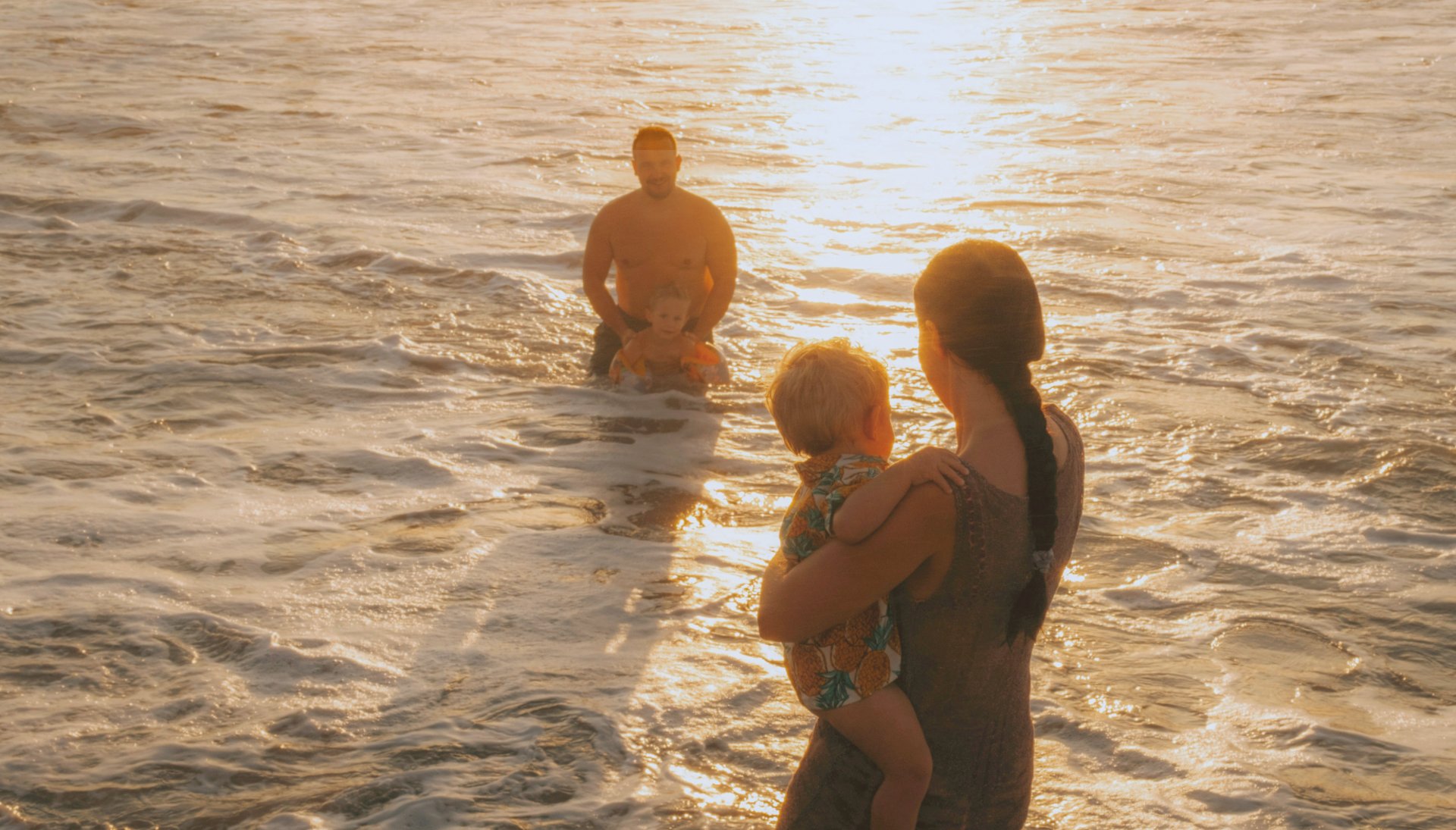 silhouetted figures of a young family in the ocean