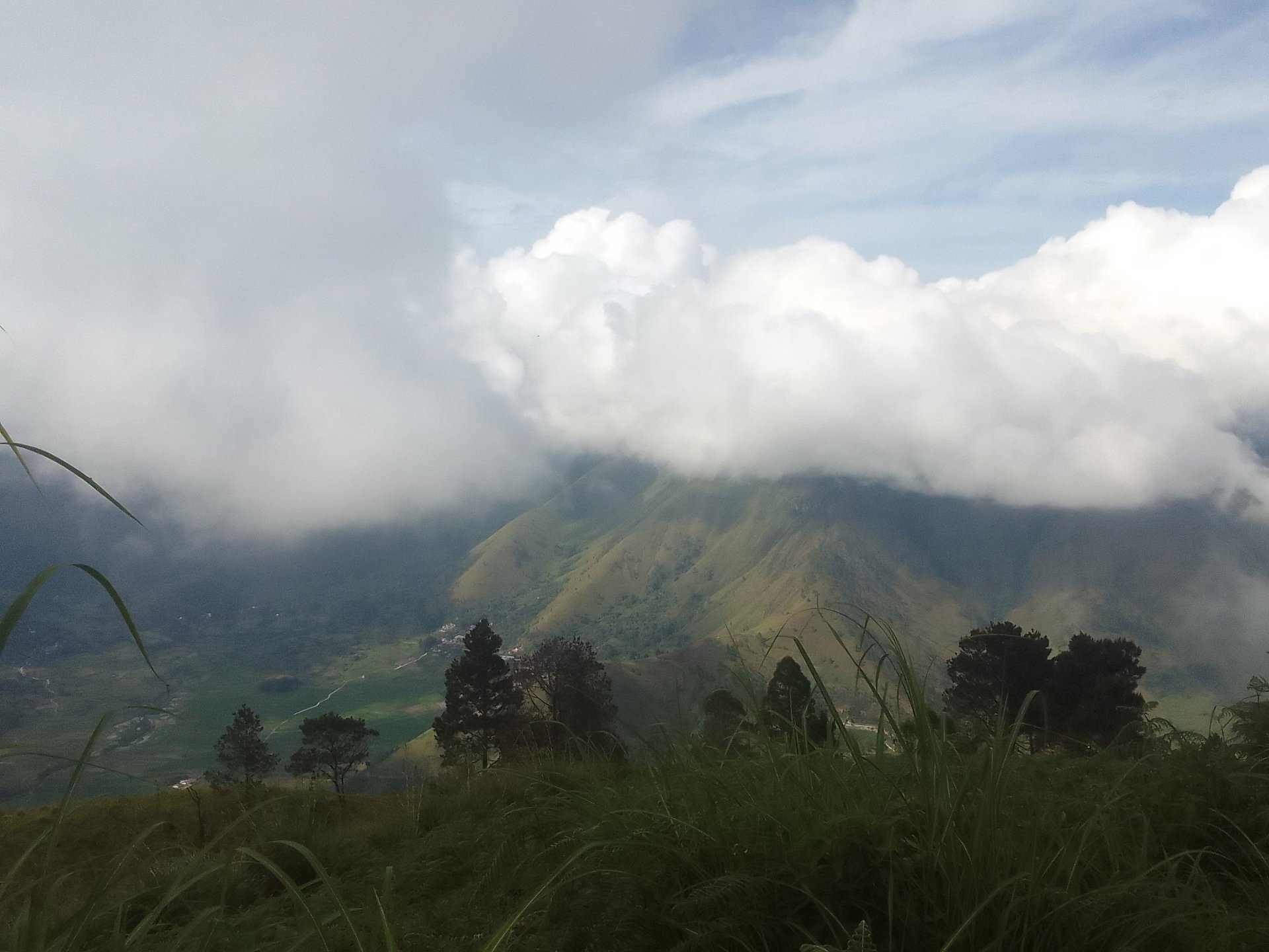 On a mountain top overlooking a valley with clouds hiding the peaks of other mountains