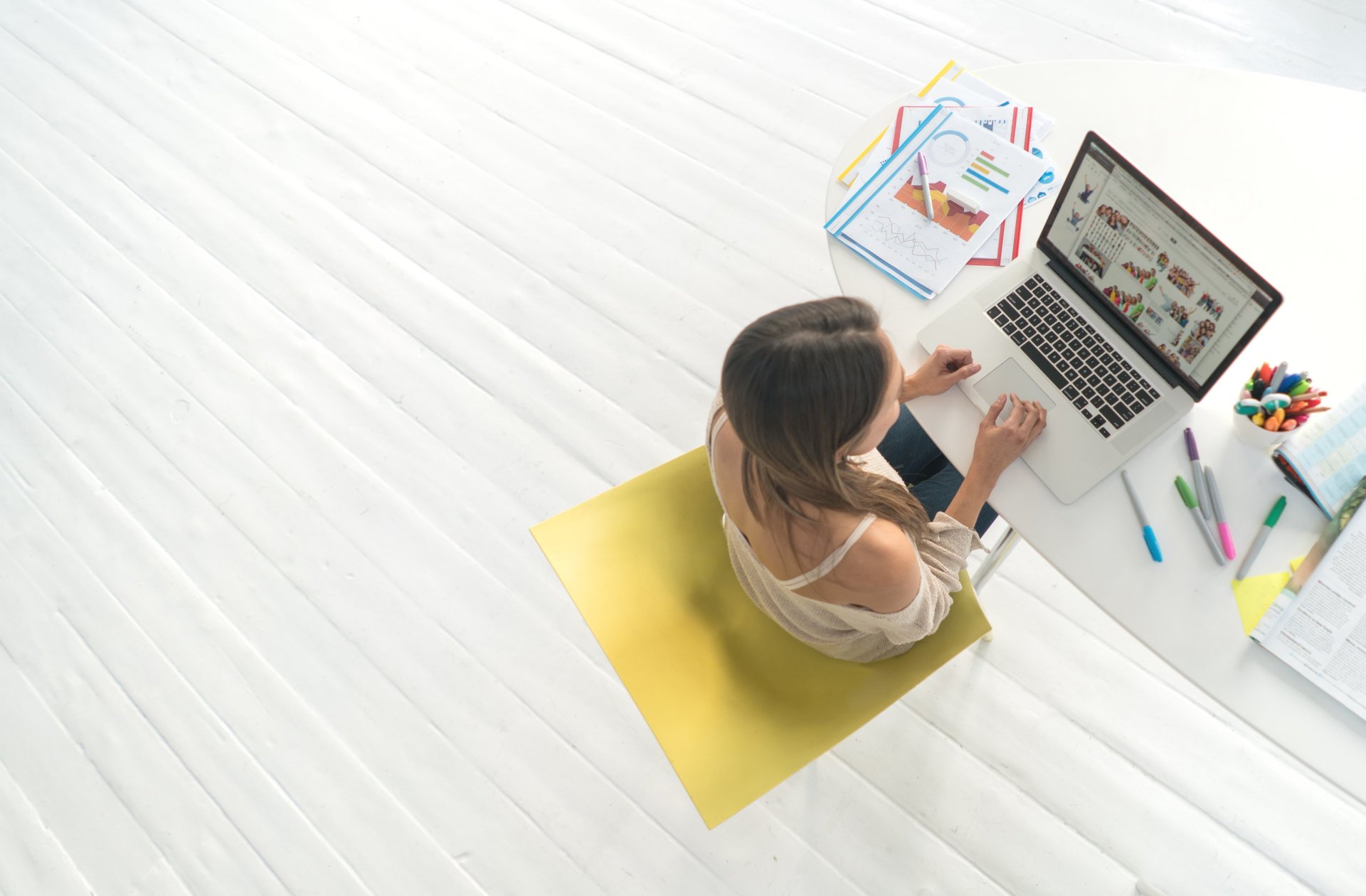 Woman wearing headphones works on a laptop at a desk.