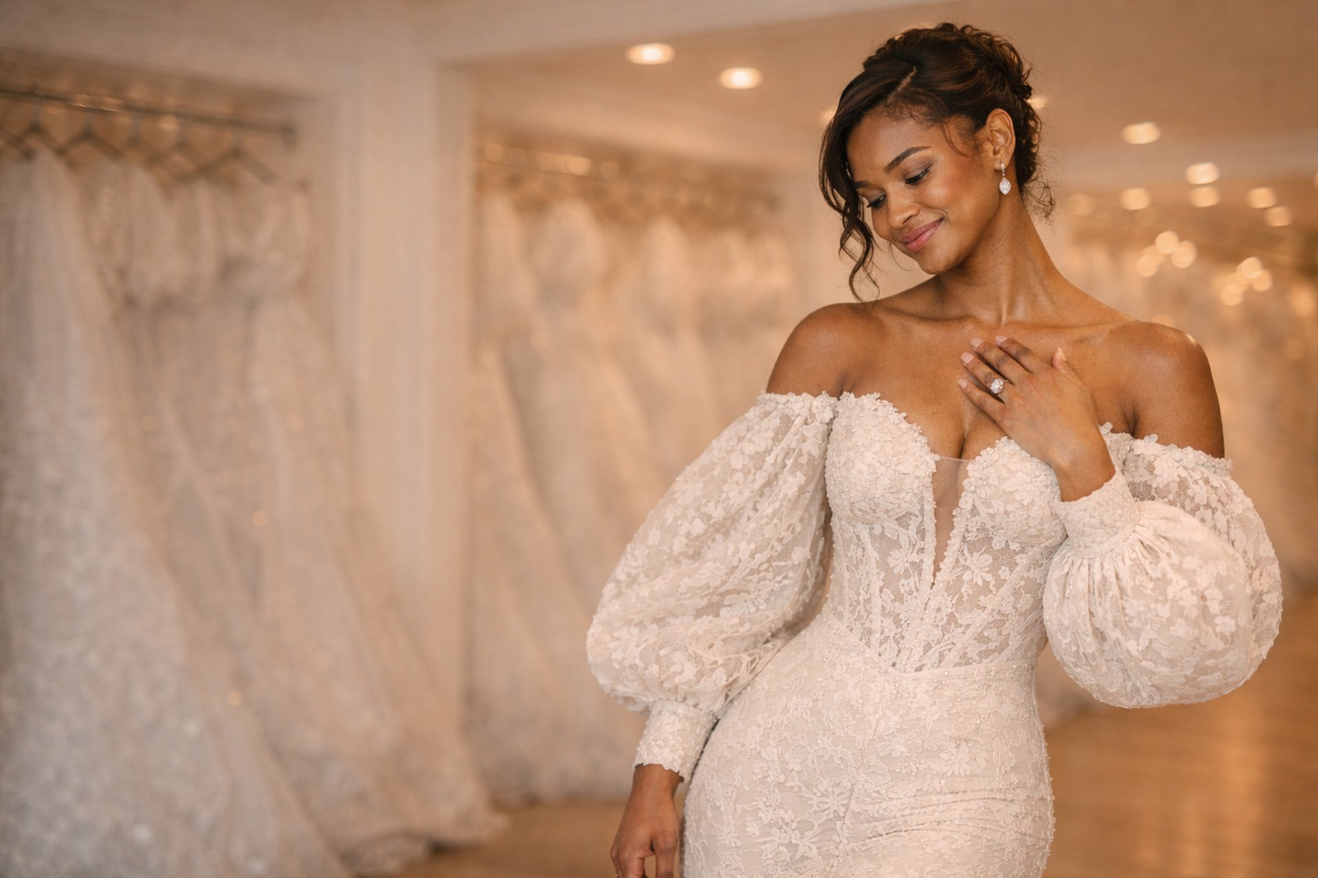 woman in wedding dress standing near window looking outside while holding the curtains