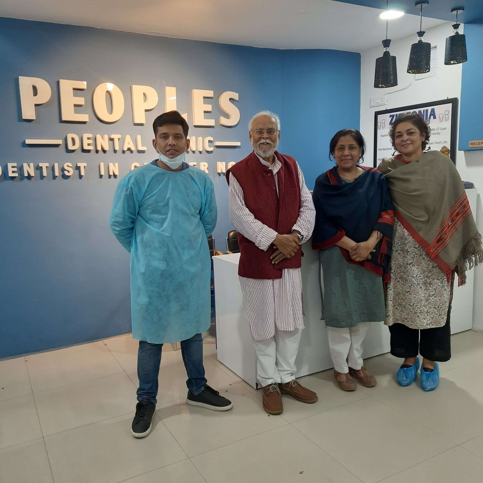 patients posing for a pic with dr ishan singh - esteemed dentist in greater noida at peoples dental clinic