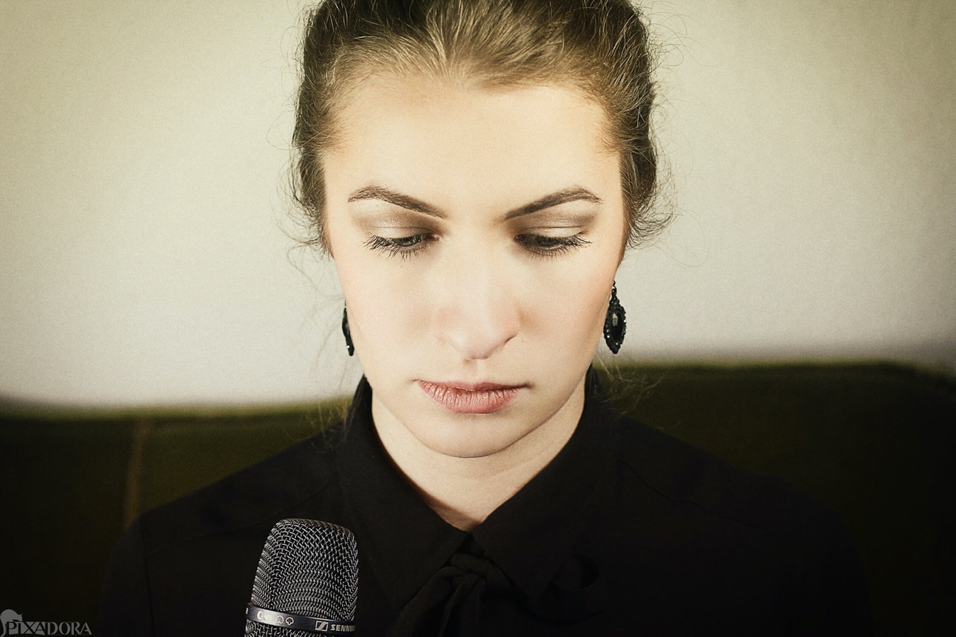 Trauerrednerin Leonie Stratmann schaut nach unten. Sie trägt eine schwarze Bluse und schwarze Ohrringe. Vor ihr ein Mikrofon.
