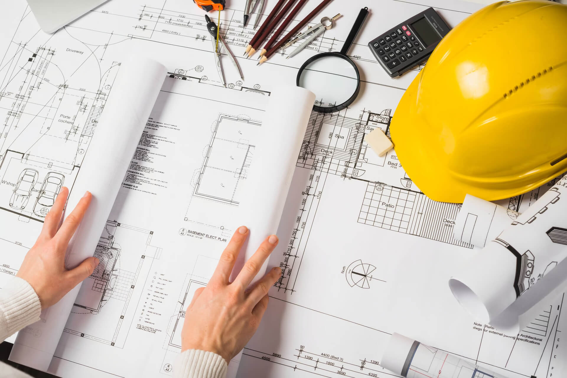 Gros plan main d'architecte ouvrant un plan de construction