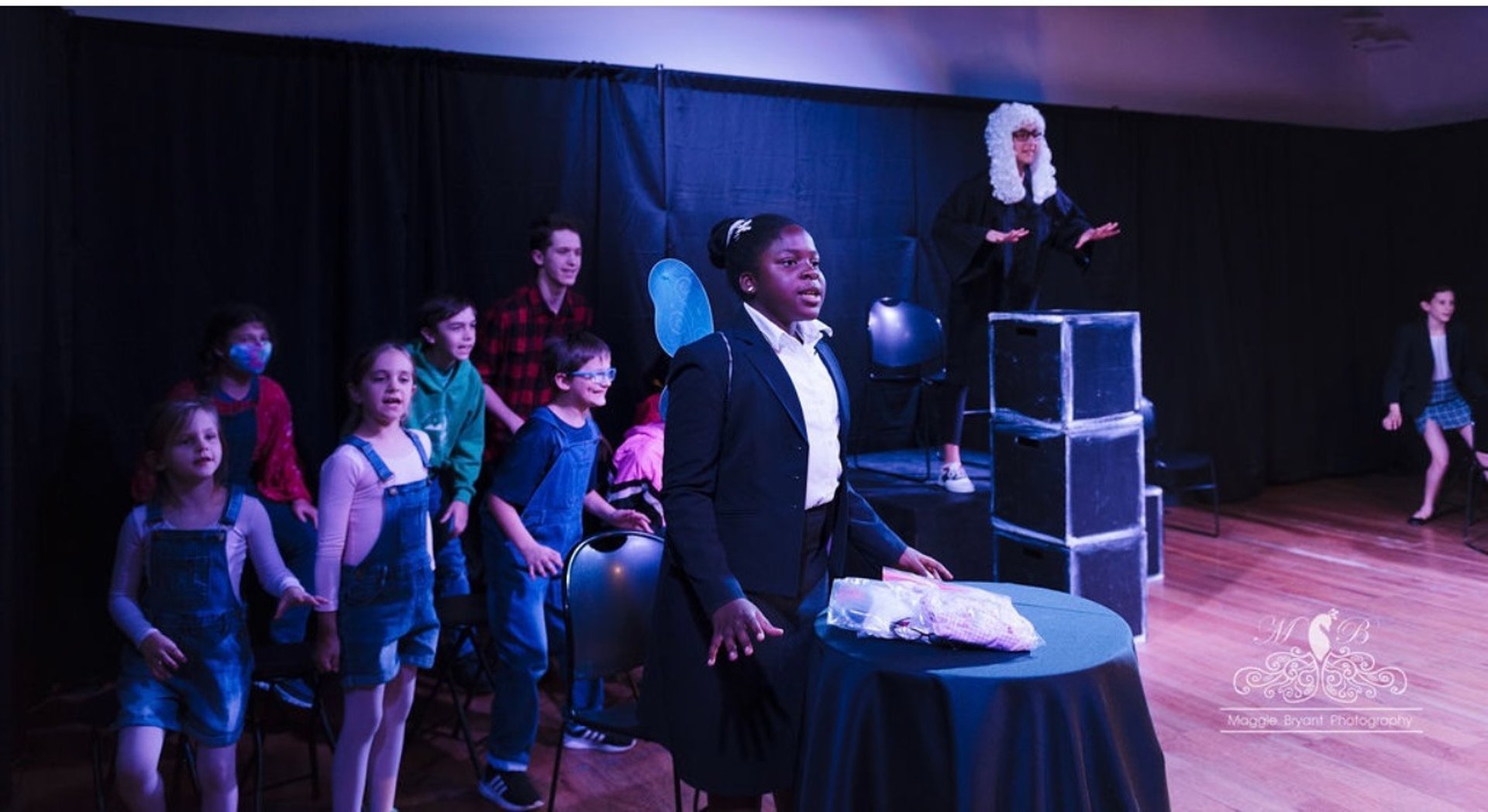 Kid actors in Big Bad the Musical in colorful costumes singing on stage.