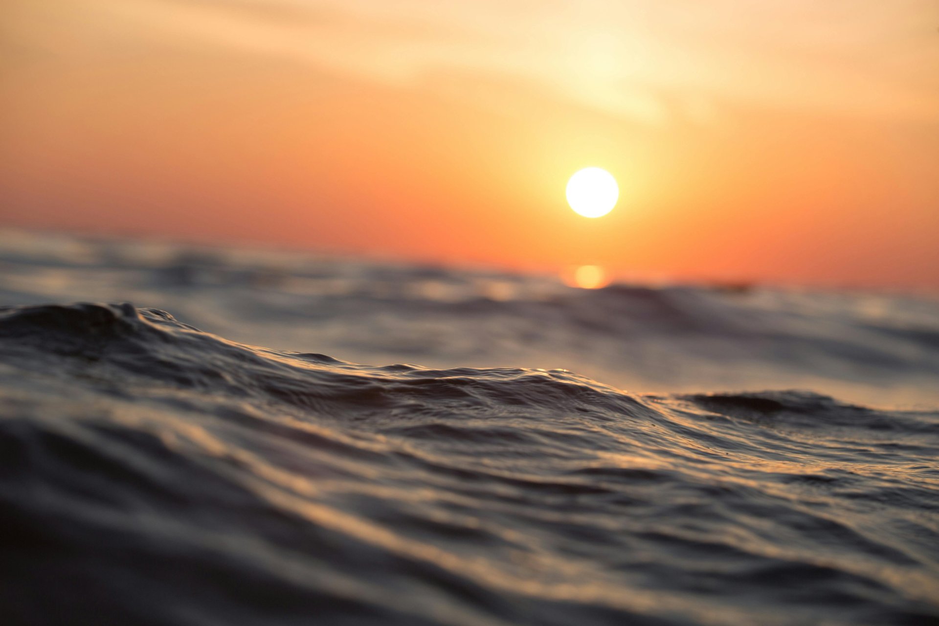 a plane flying over a body of water at sunset