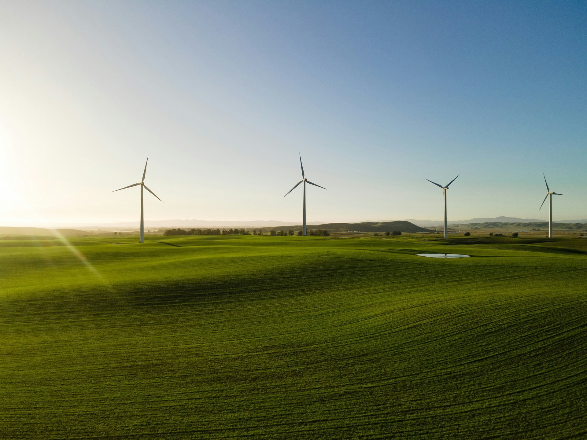 white wind turbines on brown field under blue and white sunny cloudy sky during daytime