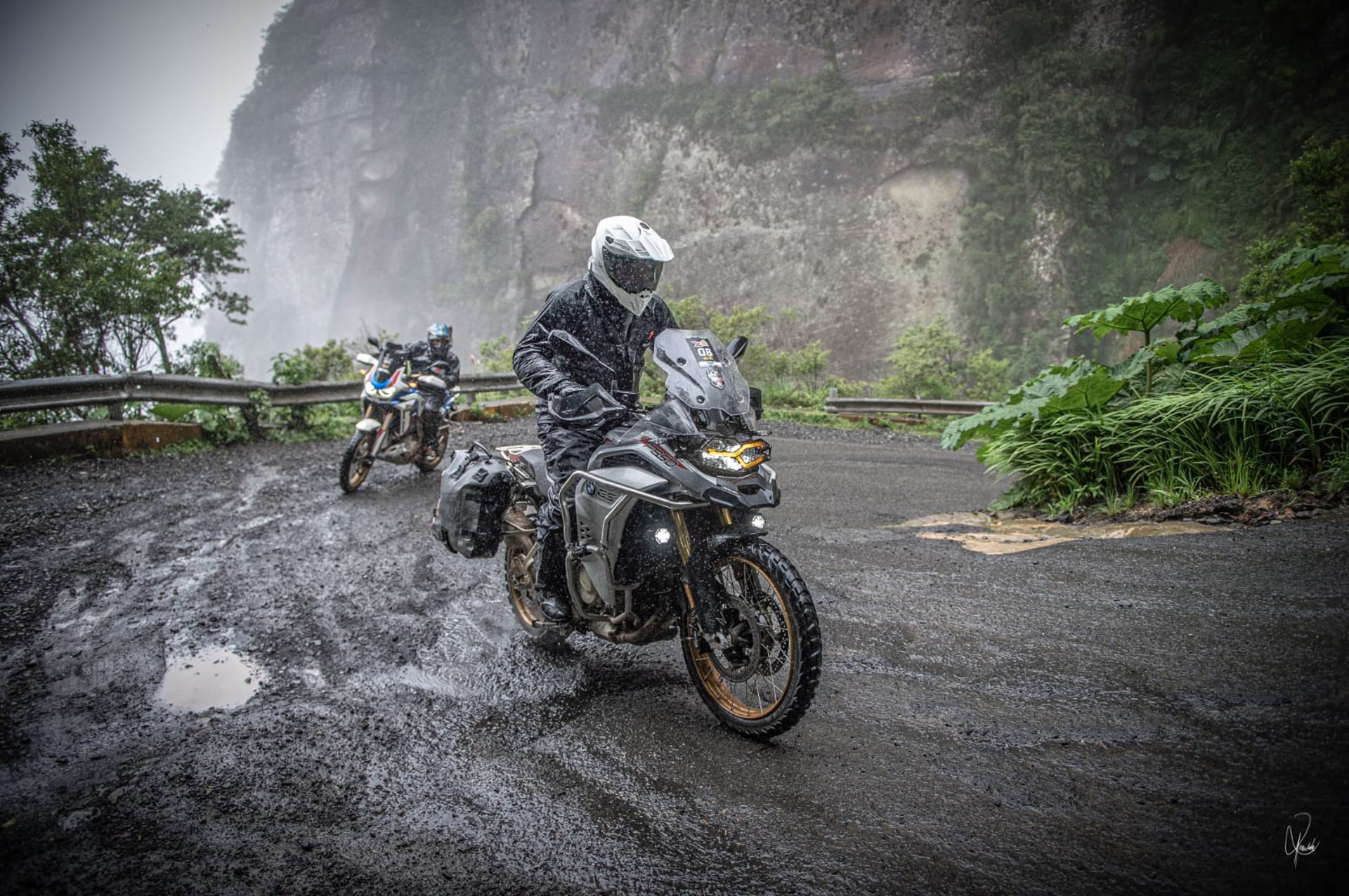 a group of people riding motorcycles on a road in a valley