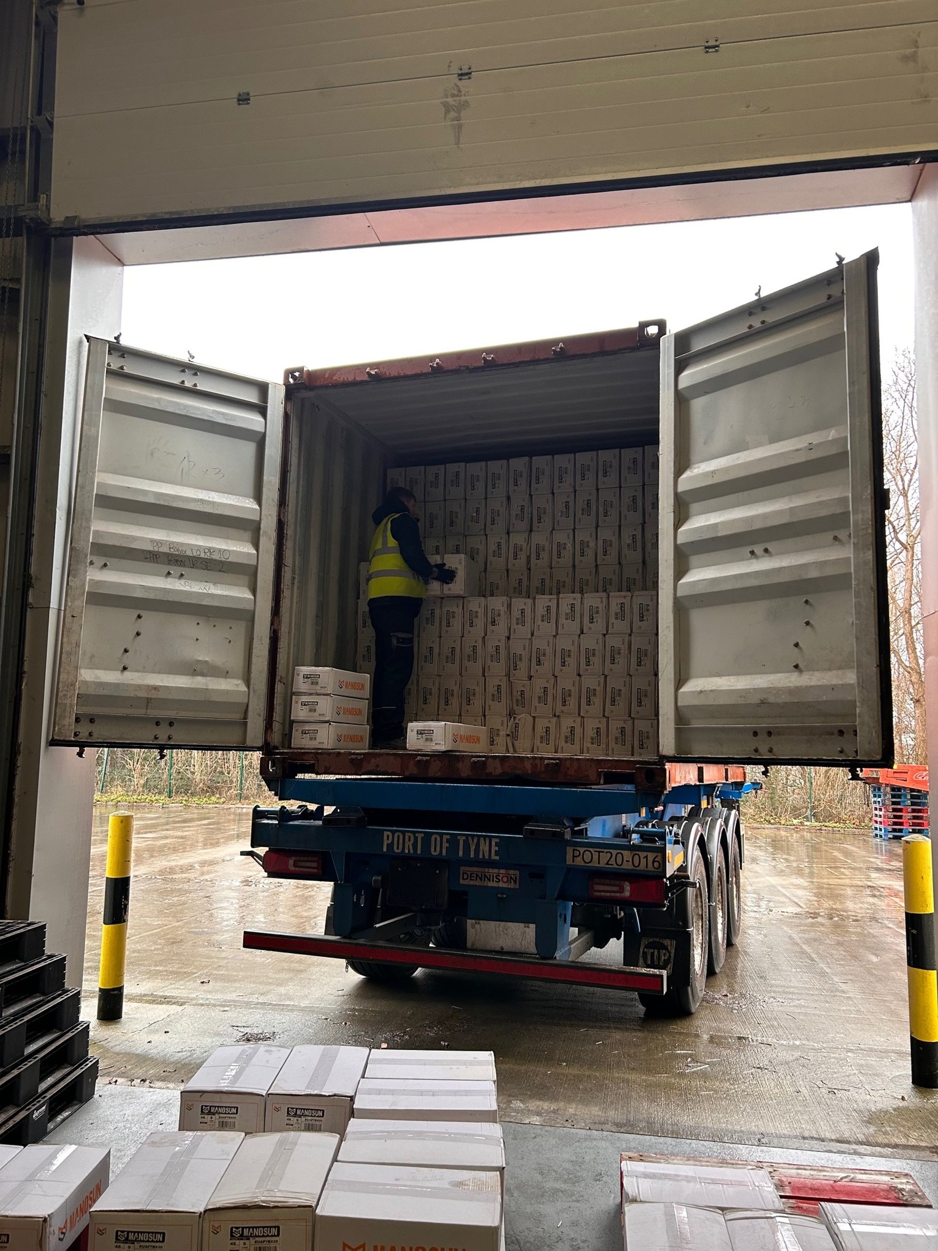 man in gray shirt standing beside brown cardboard boxes