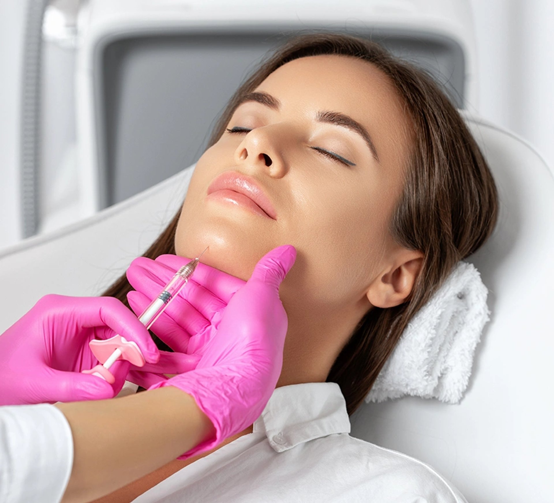 Woman receiving a chin injection from gloved hands with a syringe.