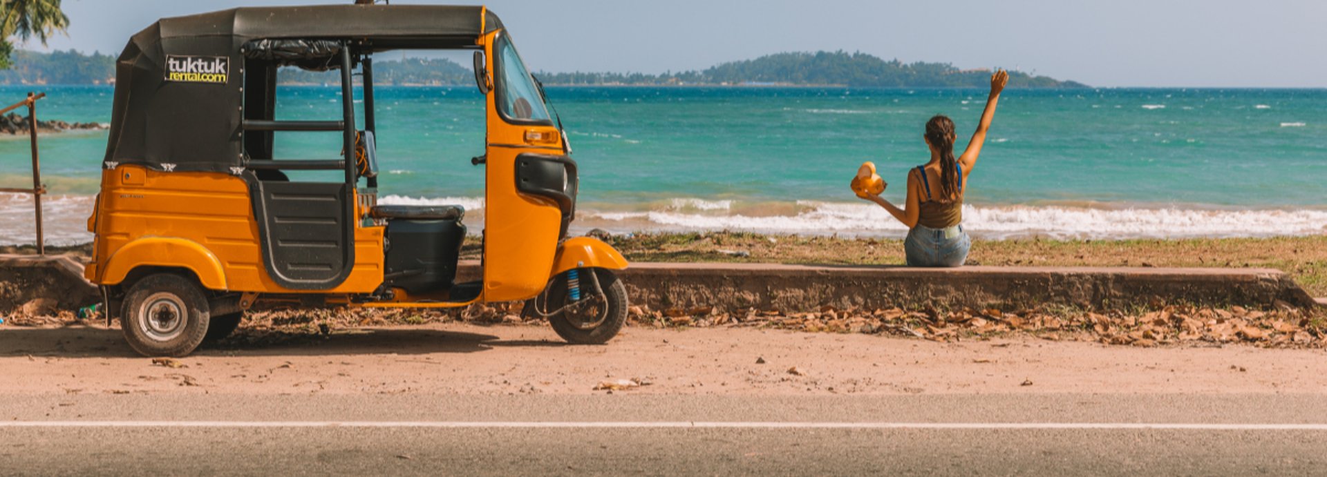 A small red car parked on the side of a beach