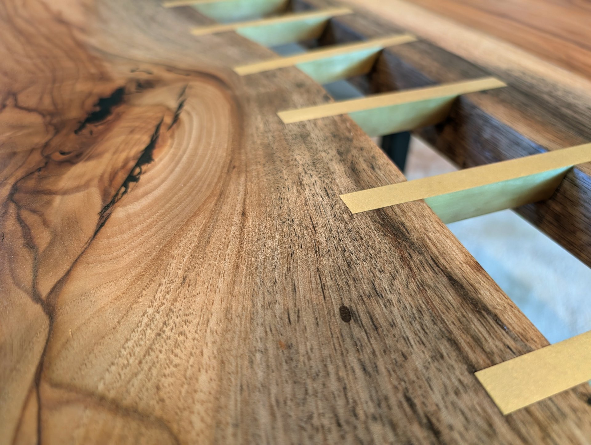 close up shot of pecan live edge river table with solid brass inlay