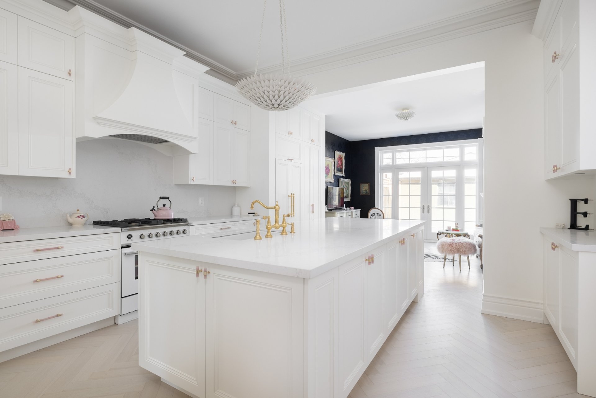 Bright white galley kitchen remodel with a quartz countertop island, deep sinks, gold faucets, and hardwood by Procon .