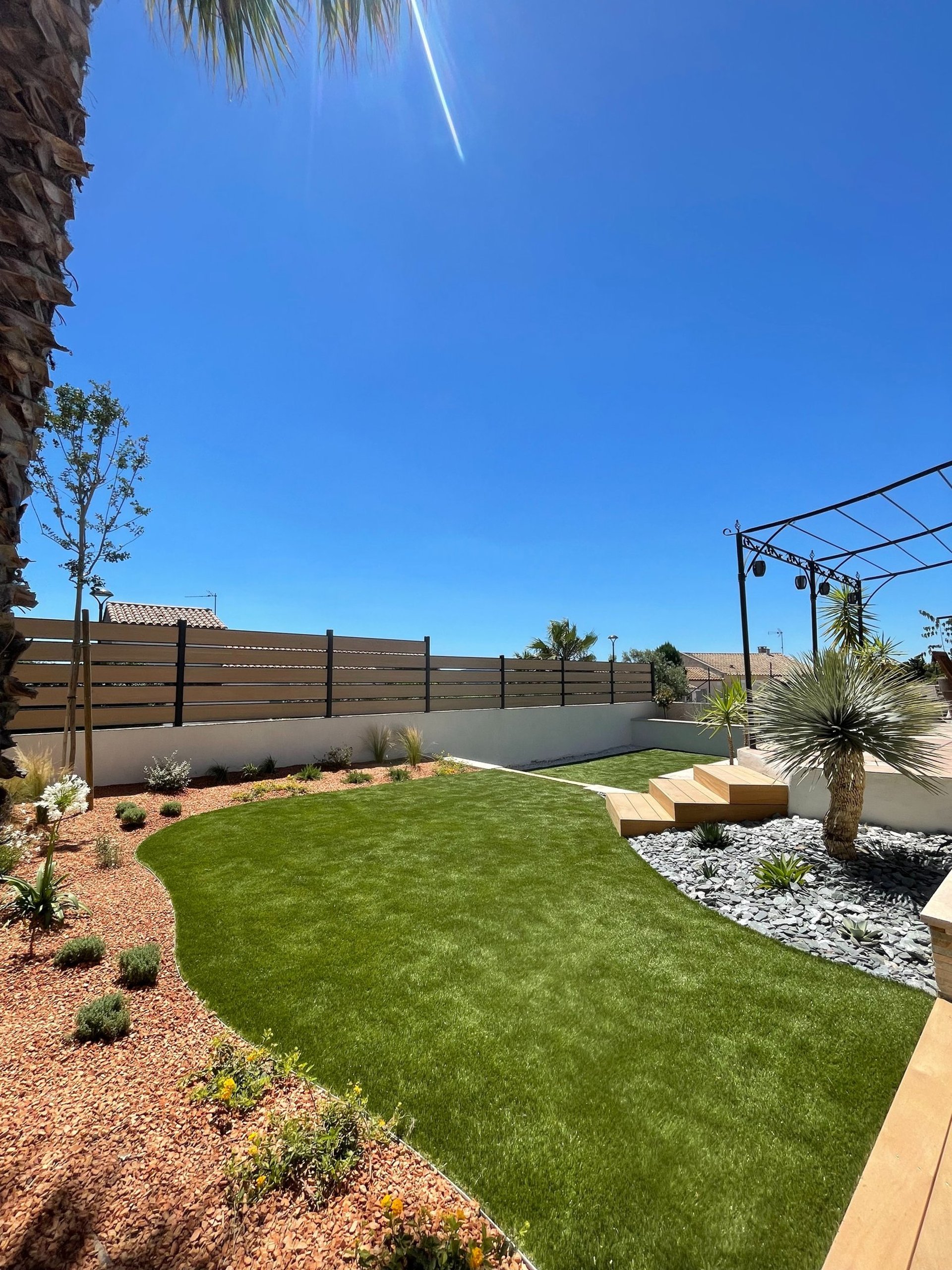 Création de jardin paysager avec gazon synthétique et massifs minéraux réalisée à Montpellier