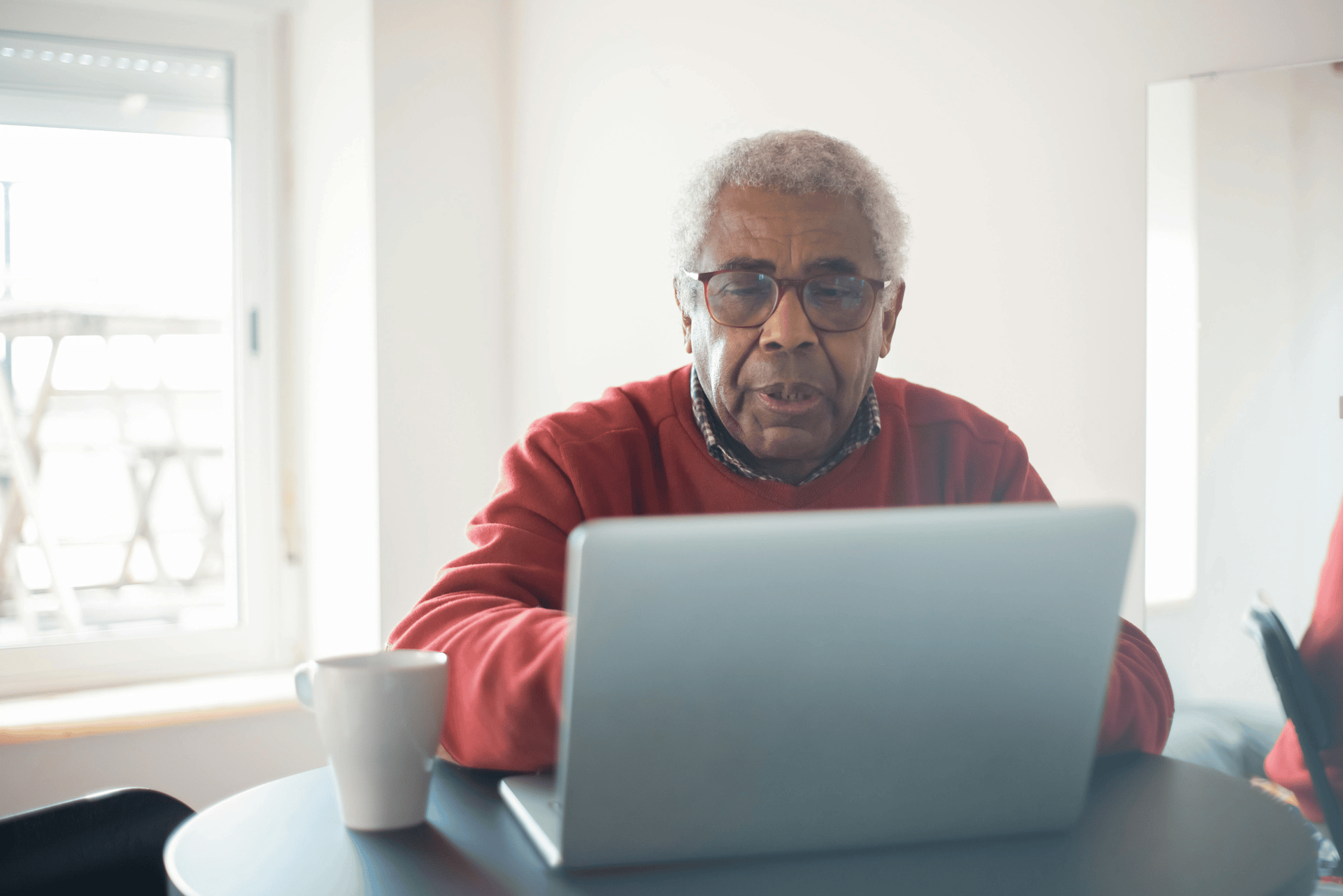 two men sitting at a table looking at a laptop