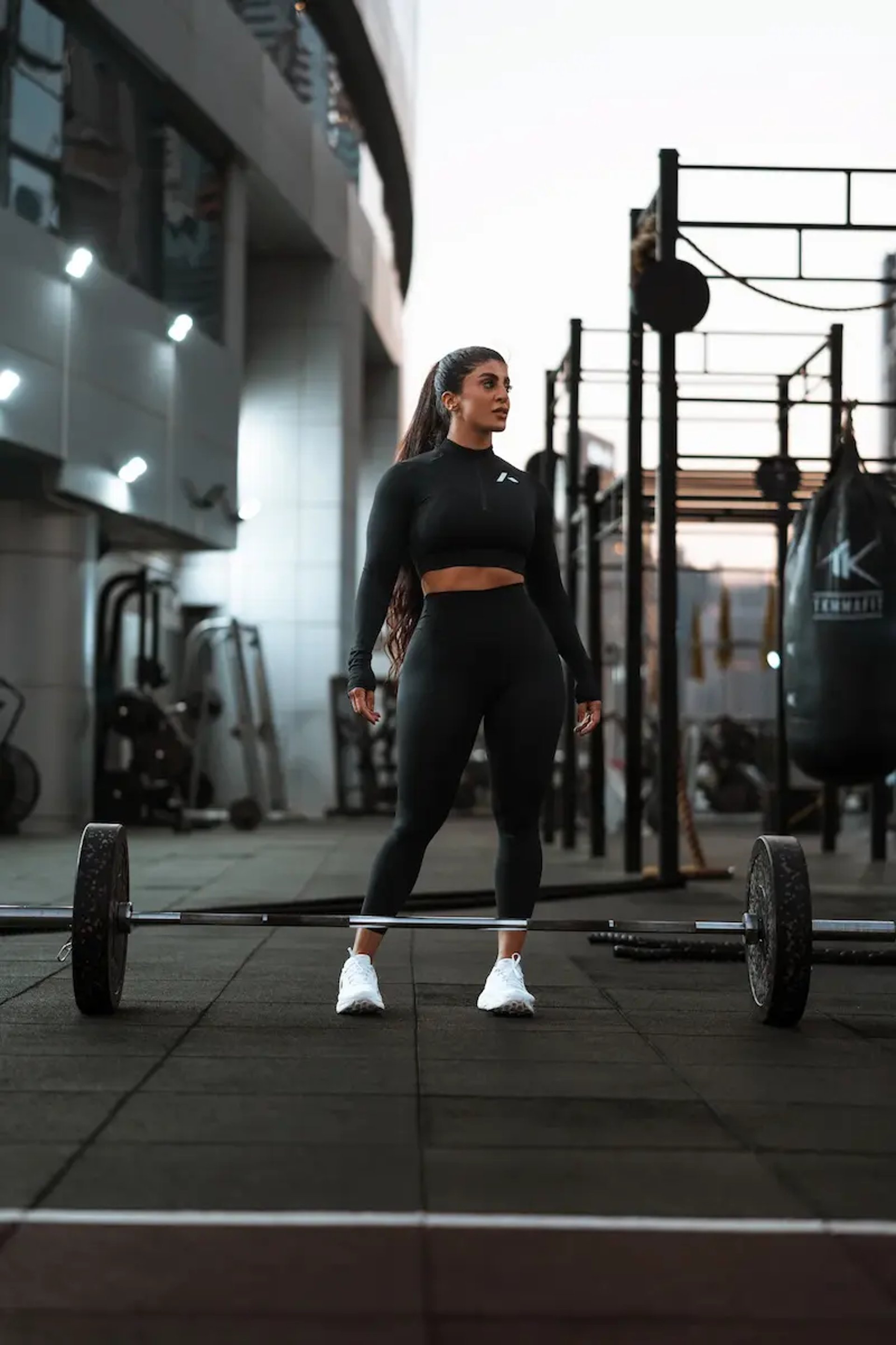 mais alhajarji wearing black sportswear standing in a gym in front of a barbell