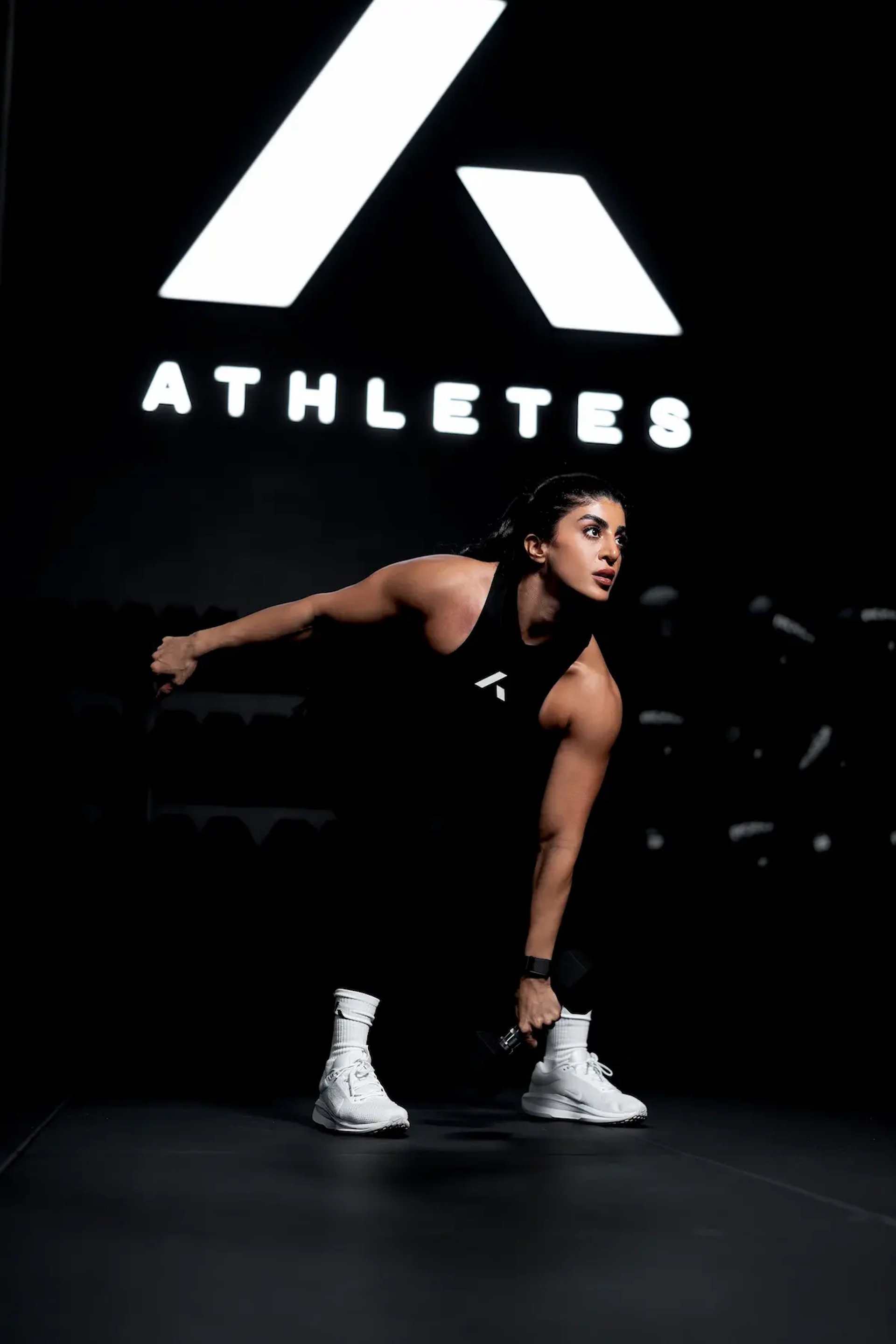 athletes training system logo with mais alhajri lifting weights in black gym outfit