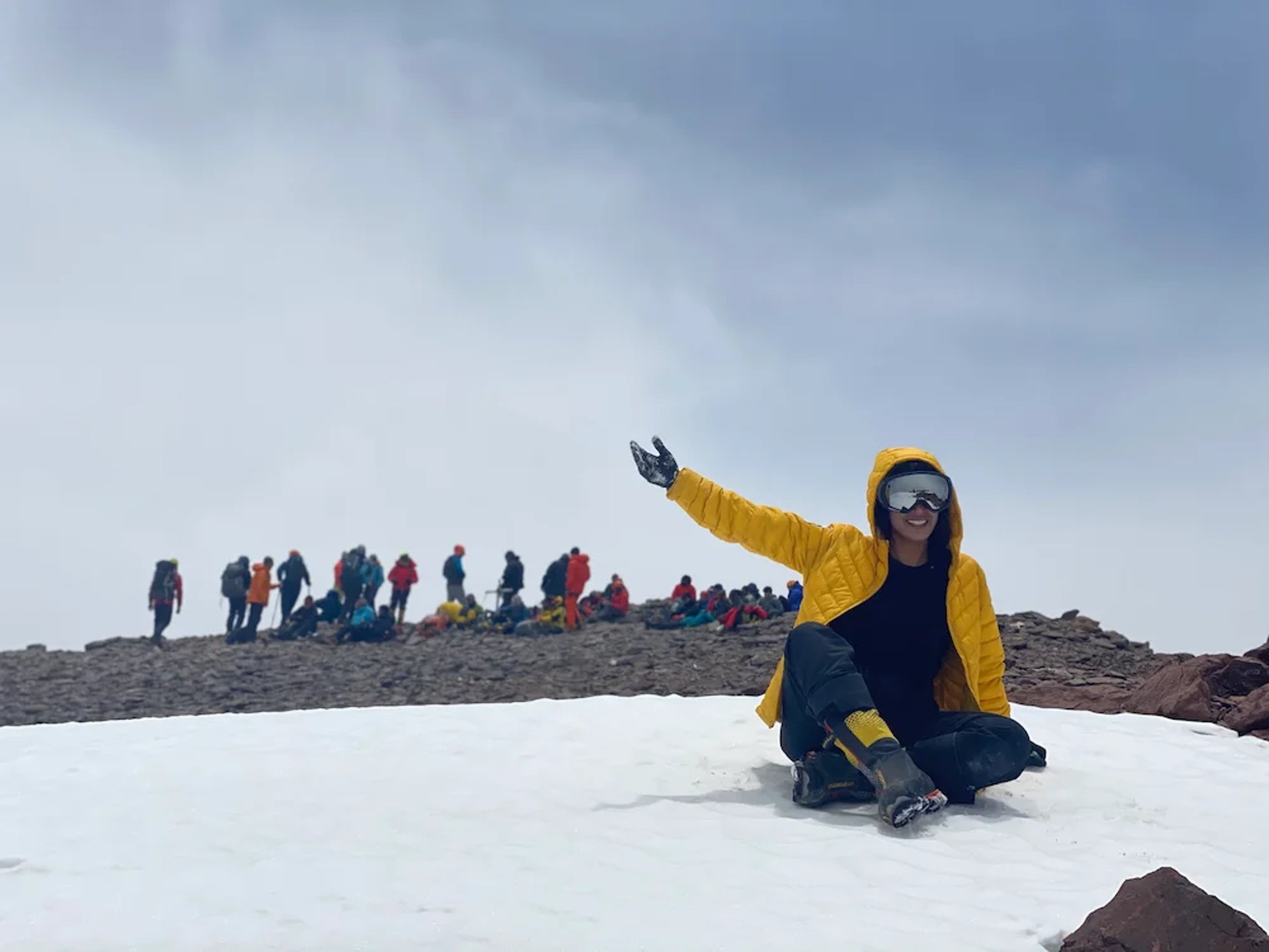 Mais Alhajri wearing yellow jacket sitting on snow