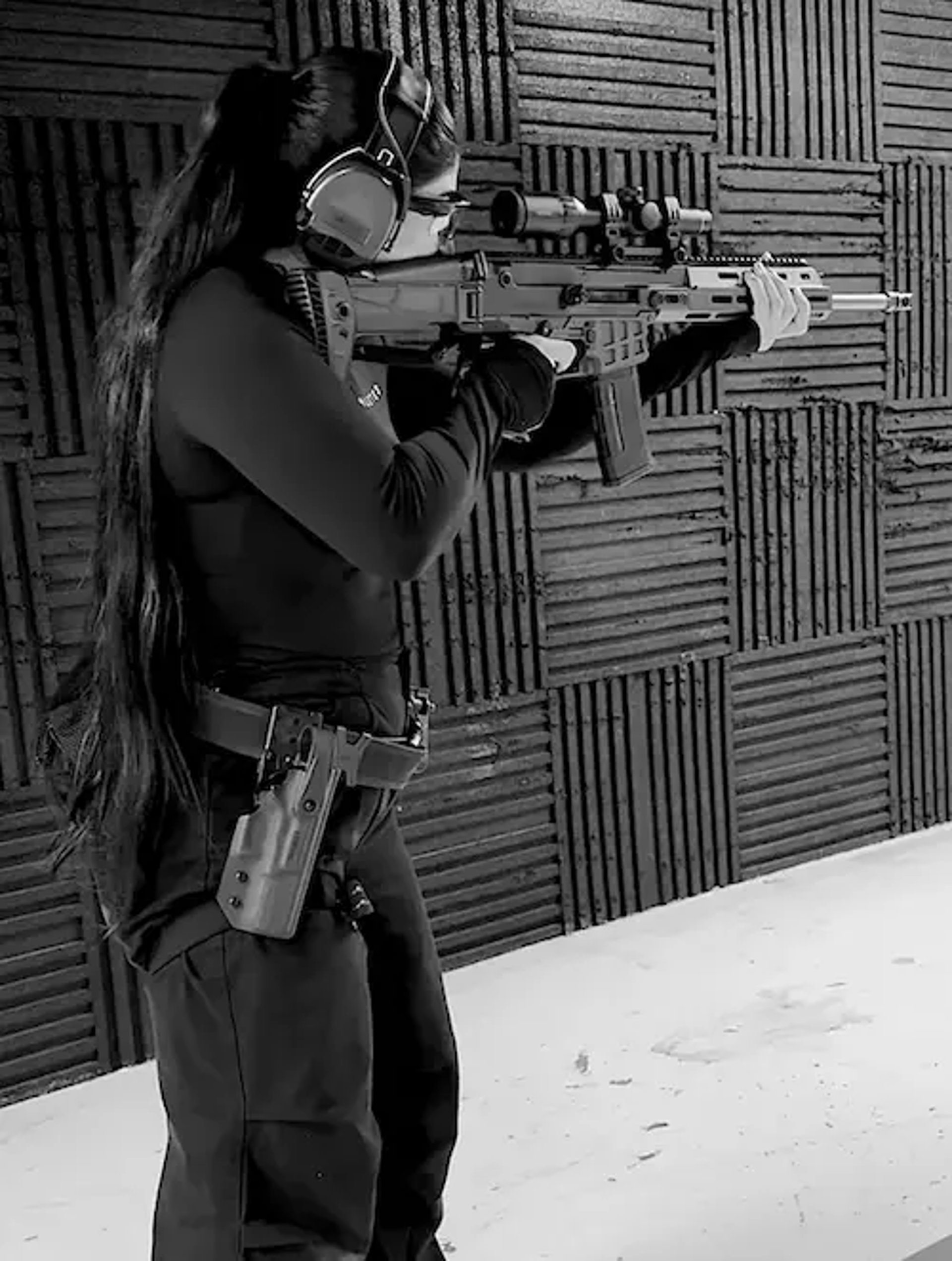 mais alhajri aiming with a rifle at a shooting range wearing safety gear