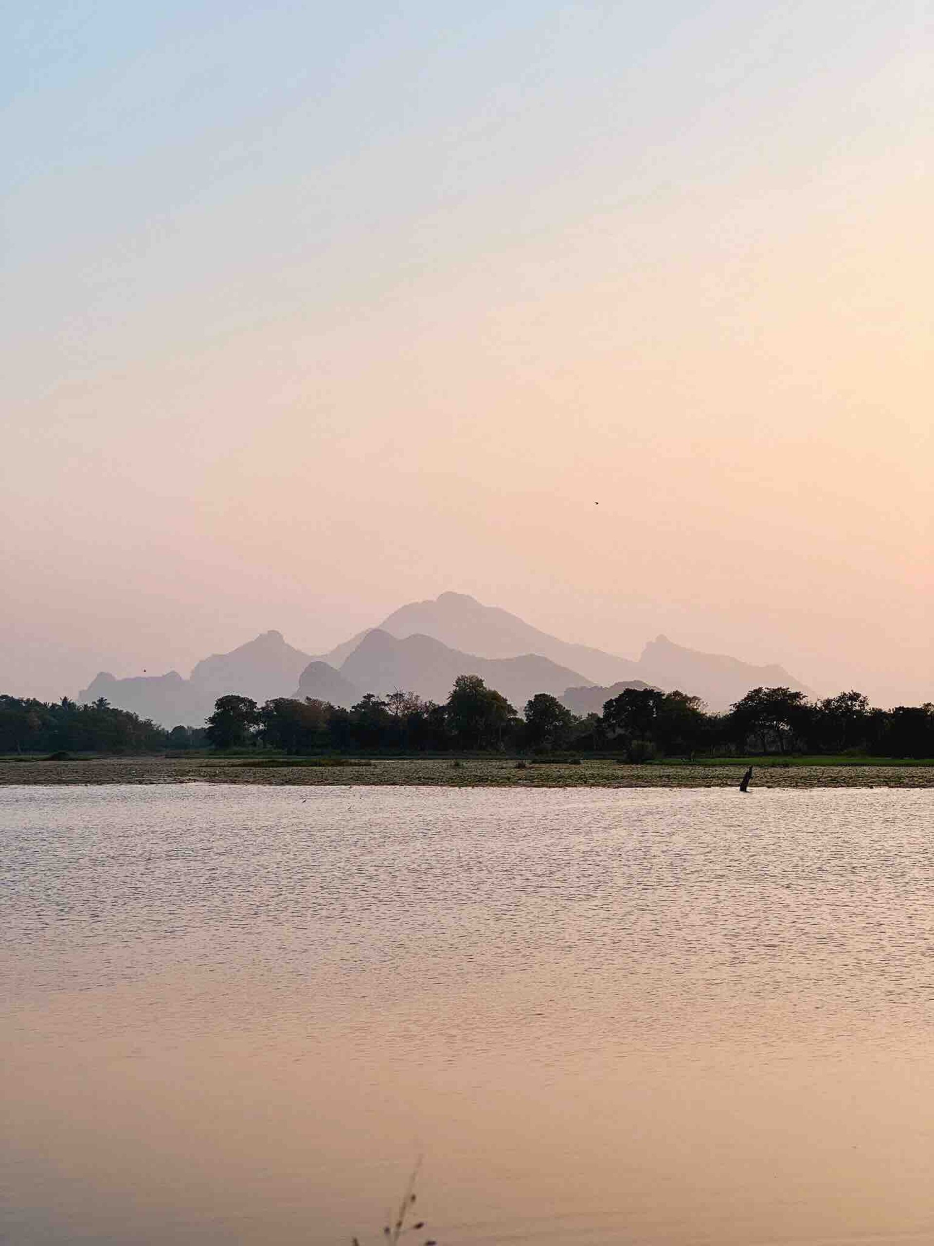 Sunset over the lake at Sigiriya, Sri Lanka, with mountains in the background.