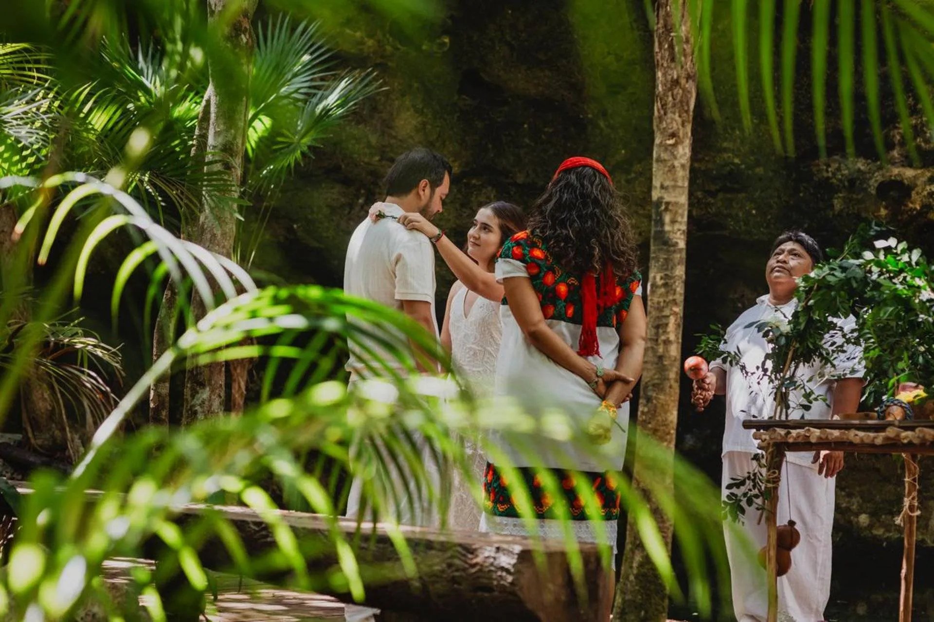 la novia bendice su pareja con una flor en una ceremonia de boda maya en un cenote