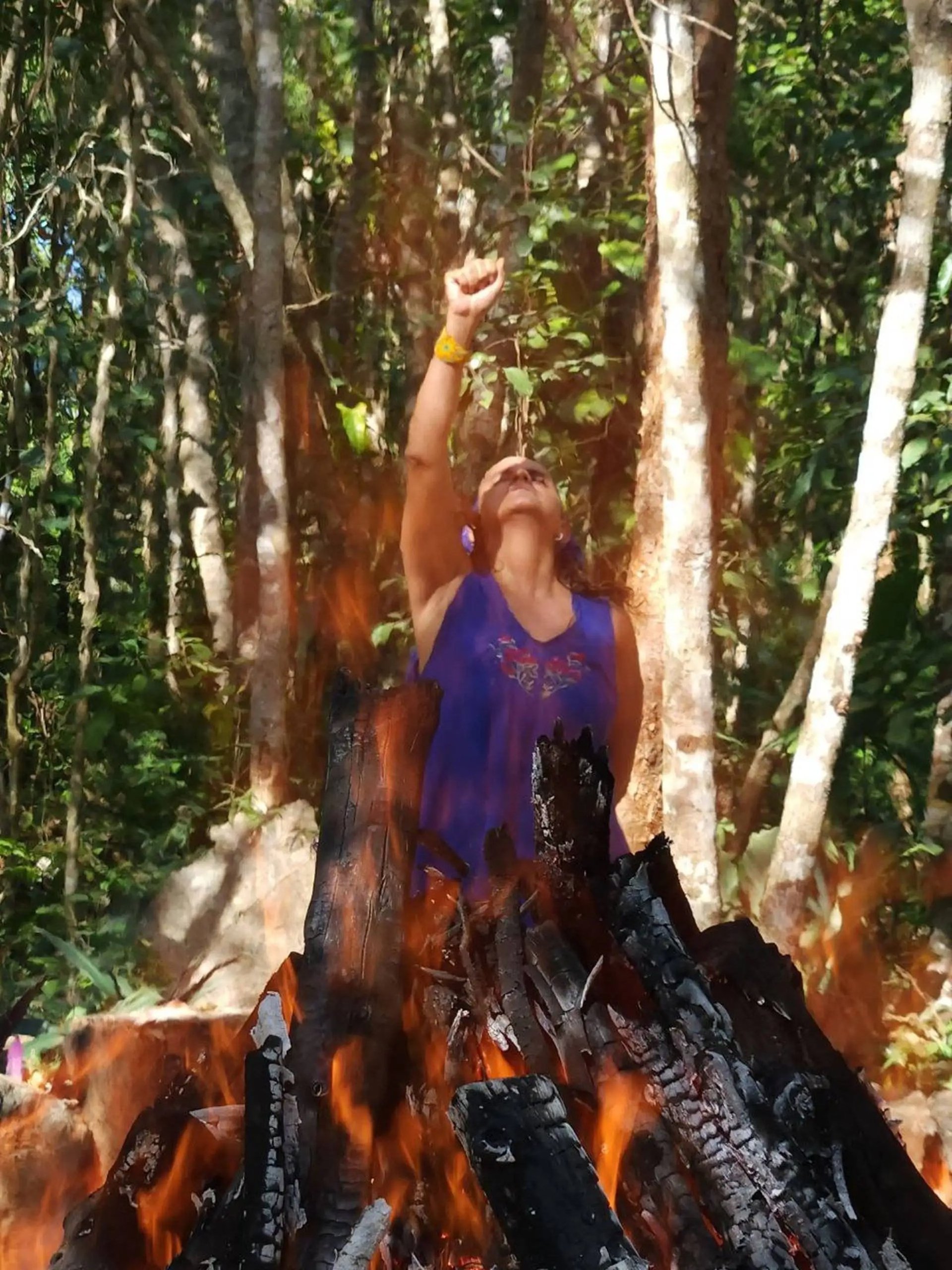 una mujer reza junto a un fuego sagrado de temazcal en la selva maya