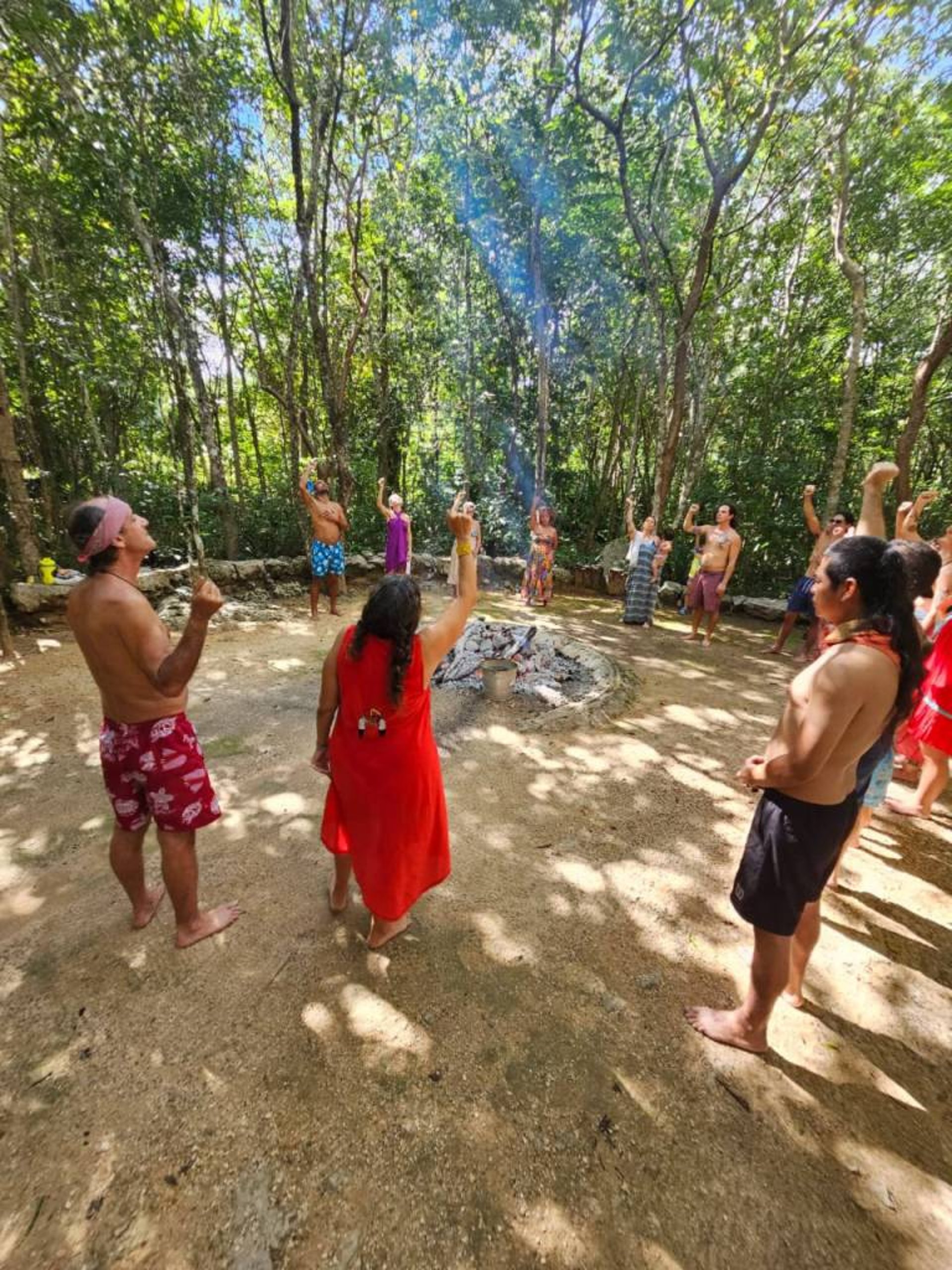 Un gruppo riunito attorno a un fuoco cerimoniale nella giungla maya per un rituale spirituale del temazcal.