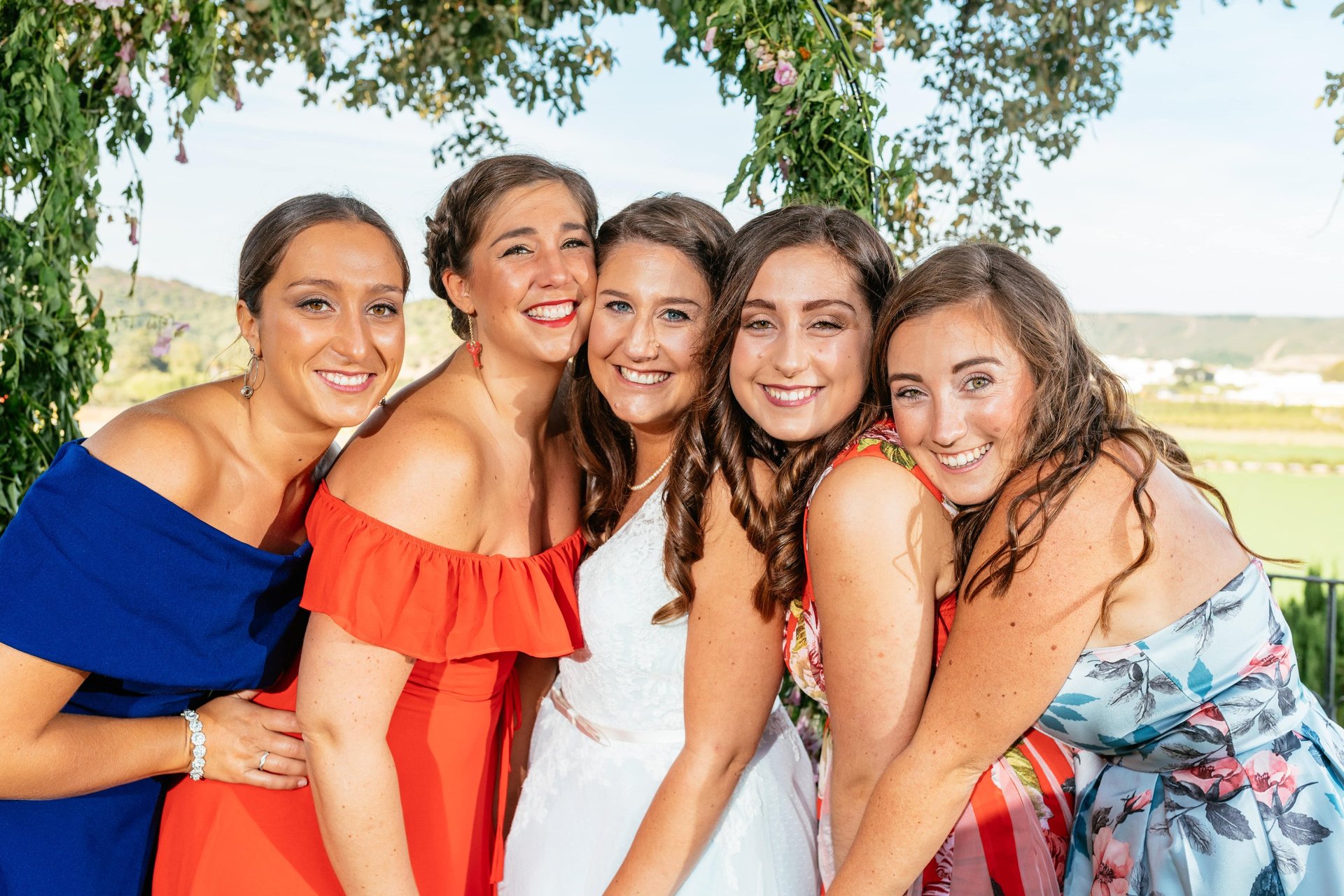 A bride and friends smiling towards the camera with heads together