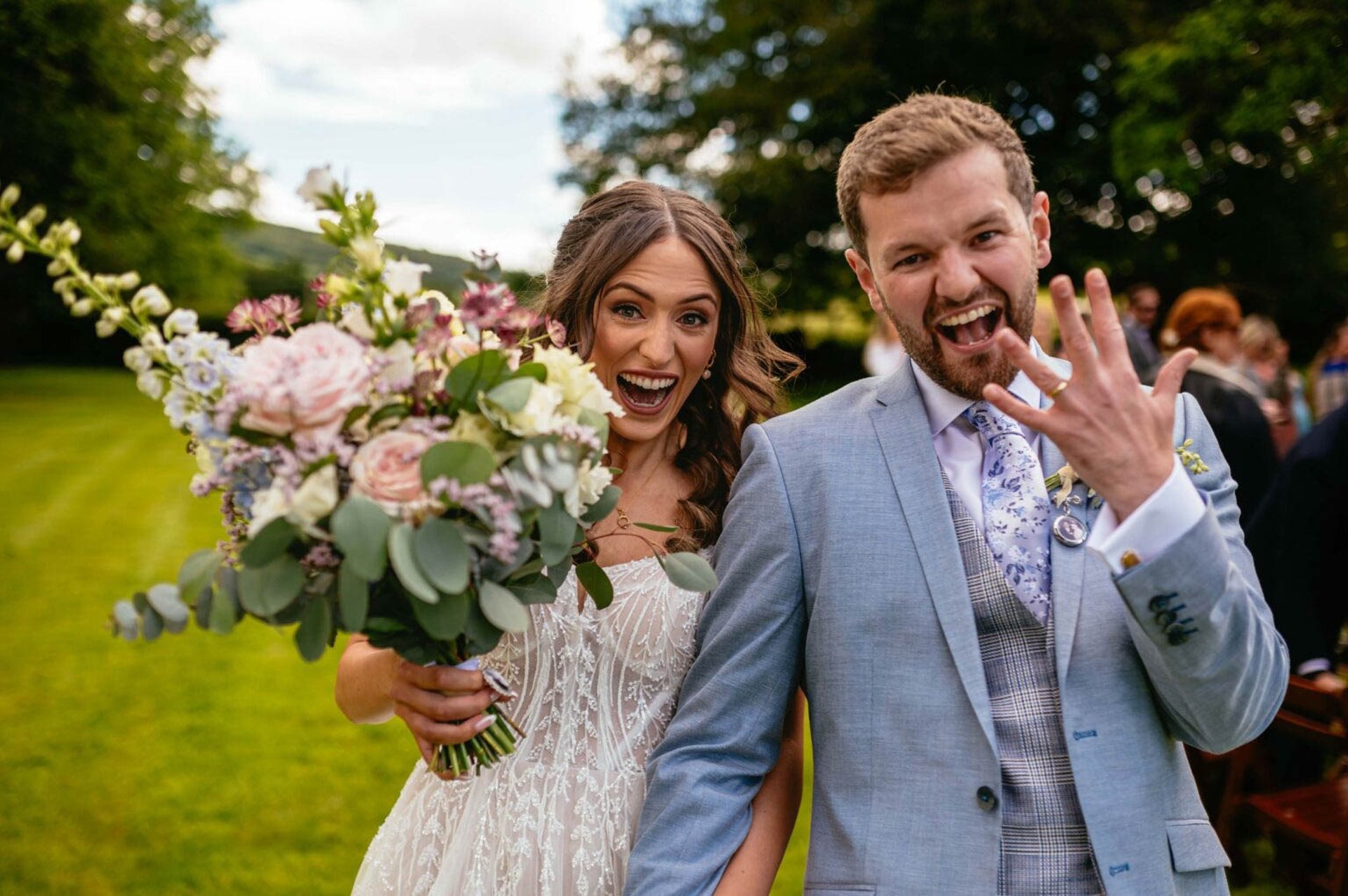 Bride and groom celebrating by showing off ring at outdoor wedding in South Wales, captured candidly by wedding photographer