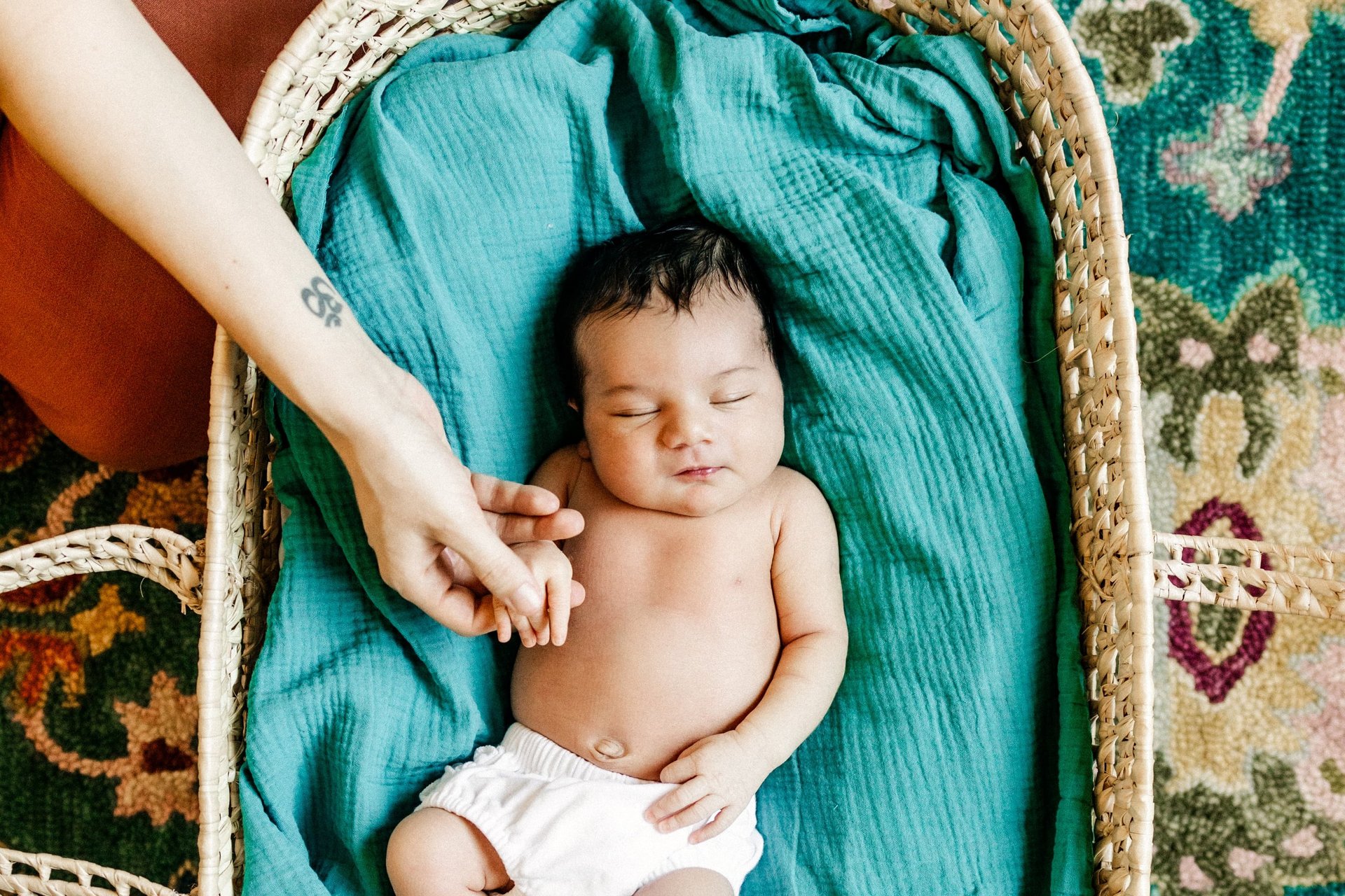 A woman is playing with a baby on a bed