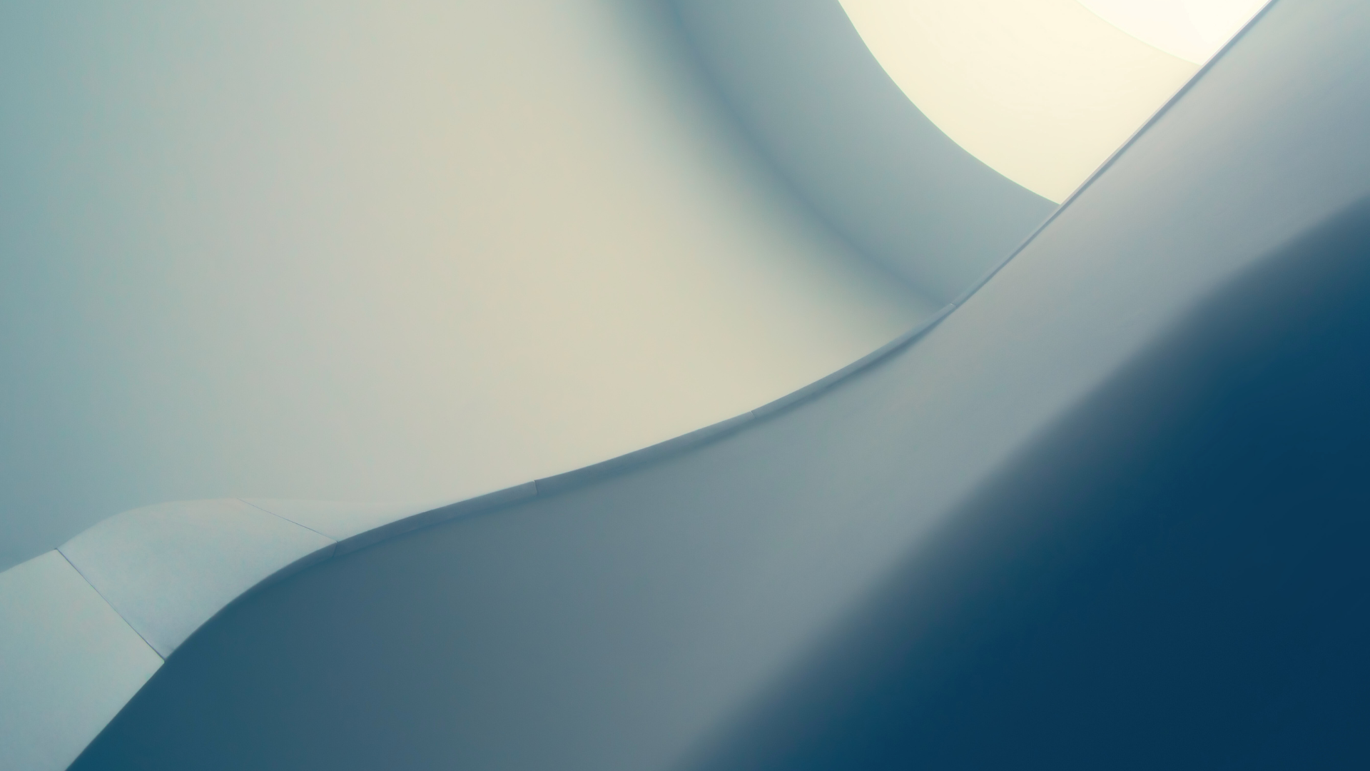 an abstract photo of a curved building with a blue sky in the background