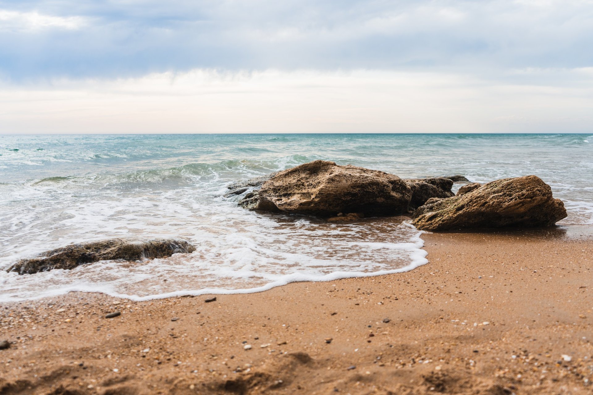 plage de sable avec deux rochers et la mer