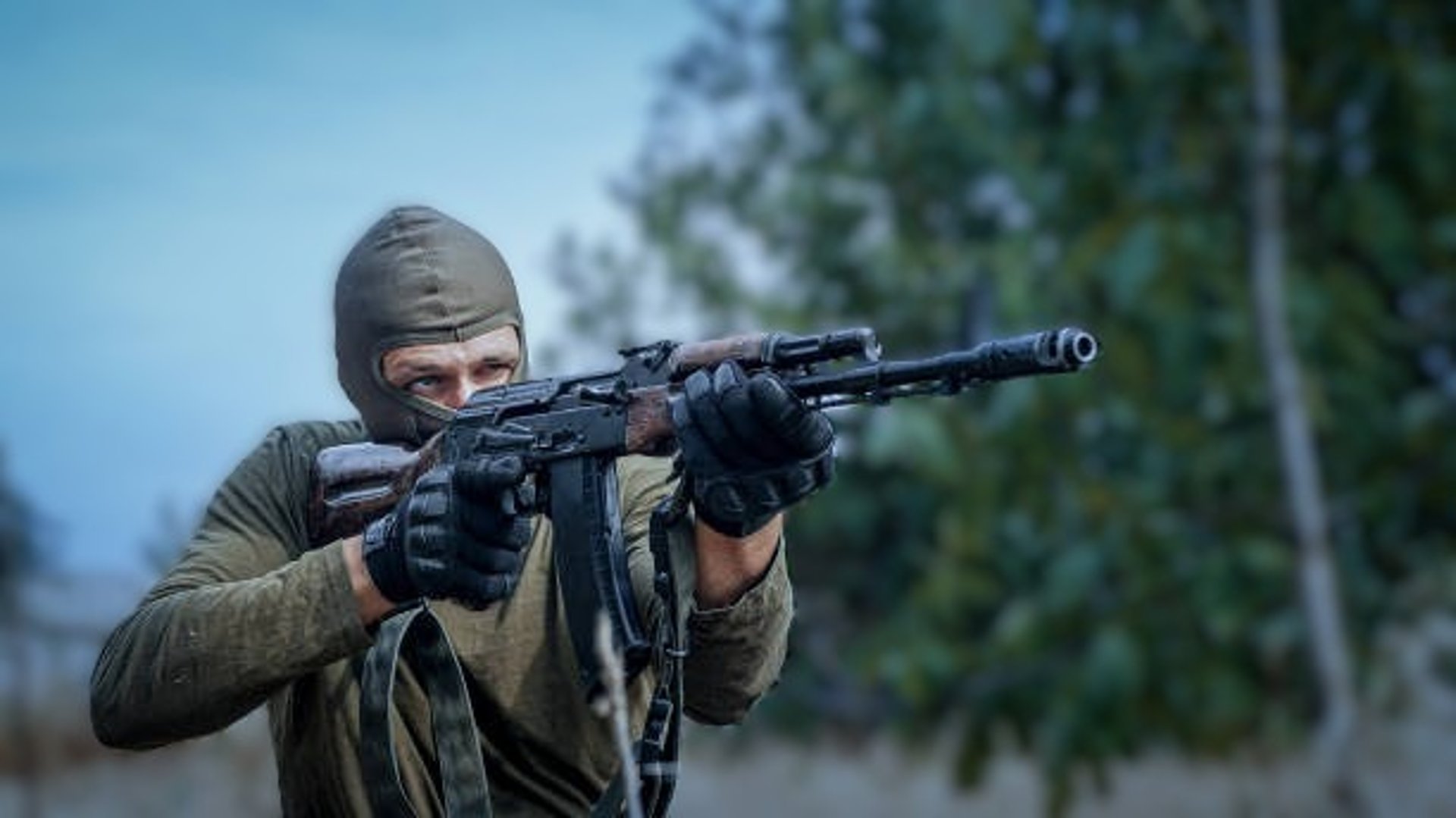 a man kneeling down with a gun and gas mask on